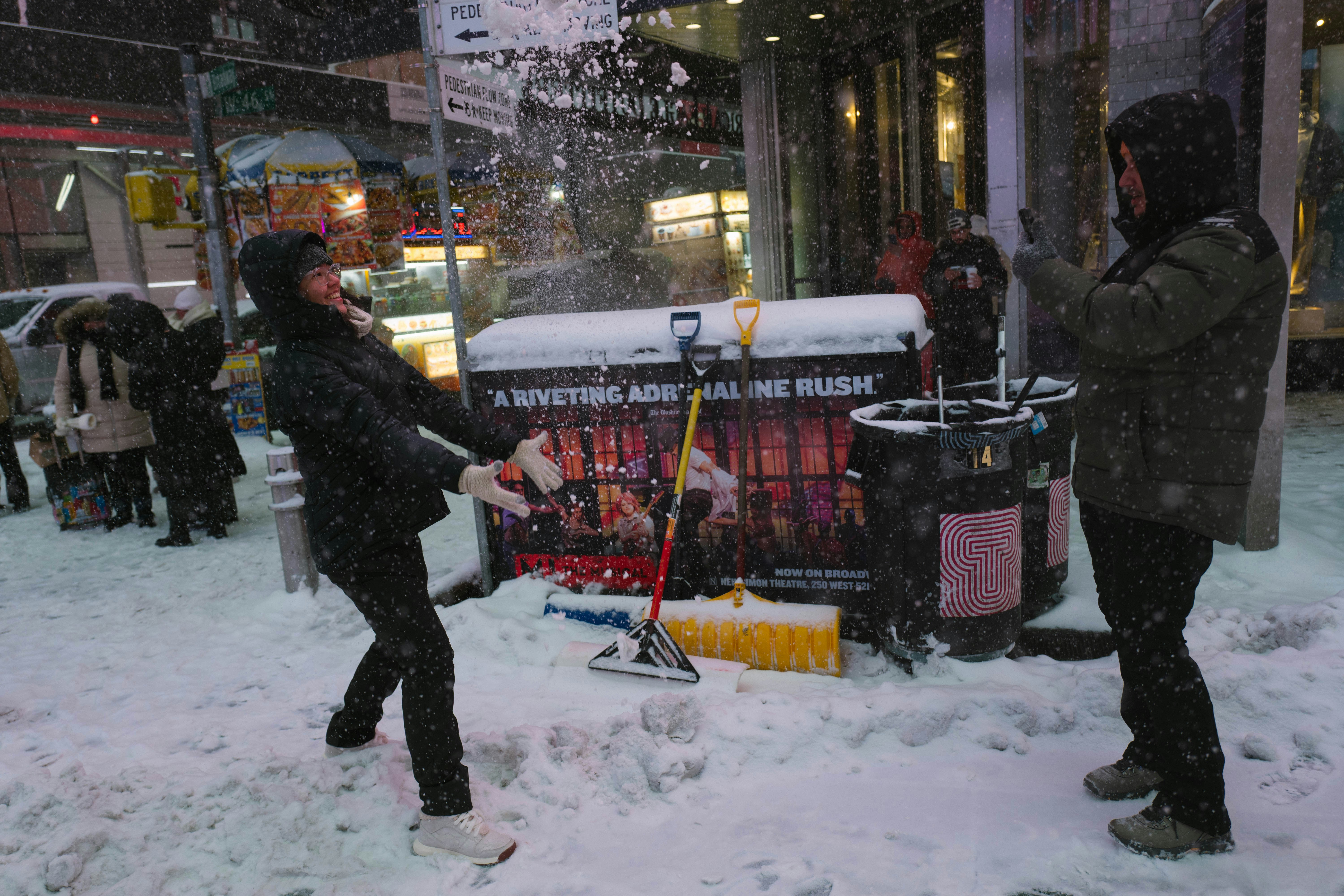 Two people playing in the snow on a city street