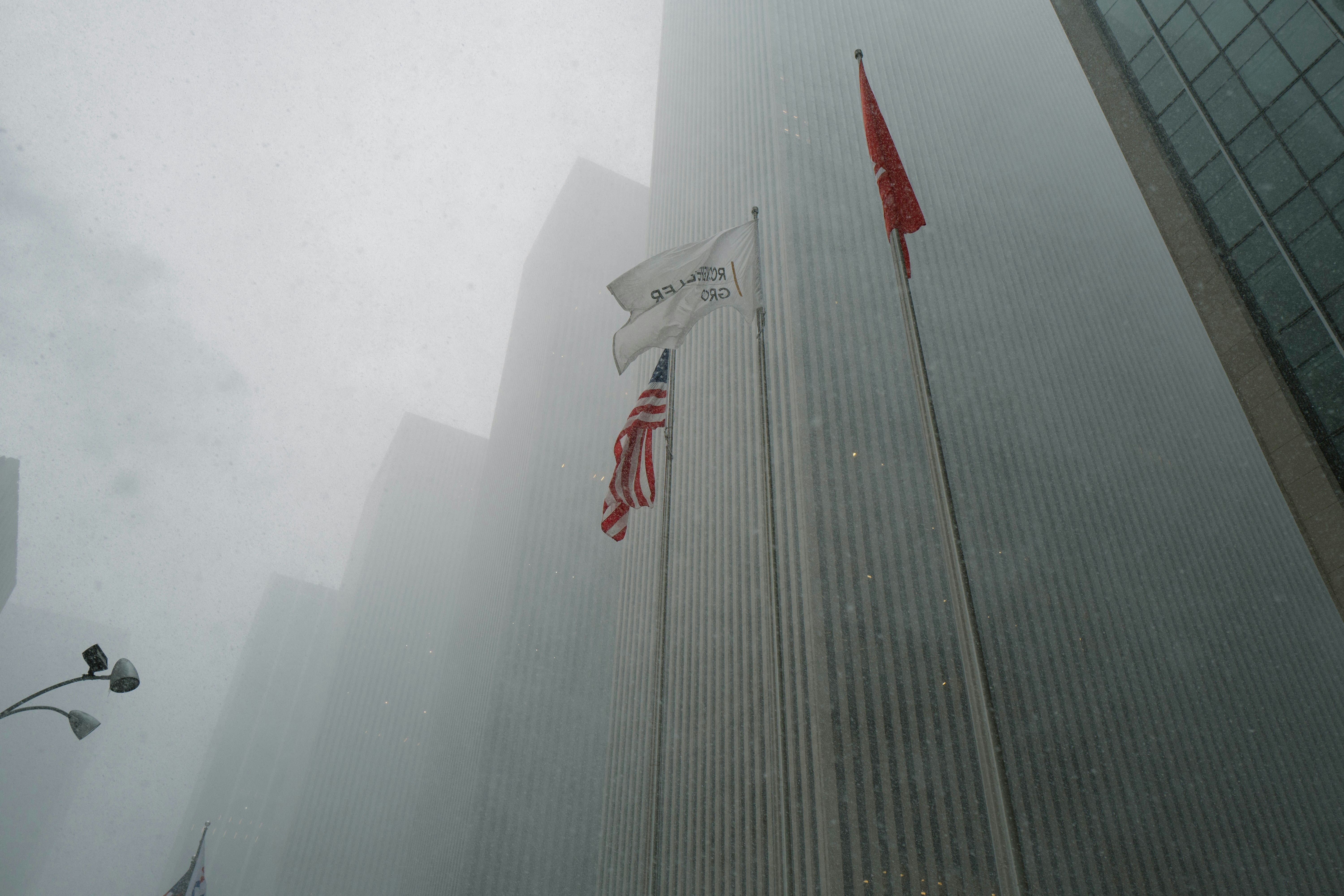 Tall buildings shrouded in fog with flags flying flags