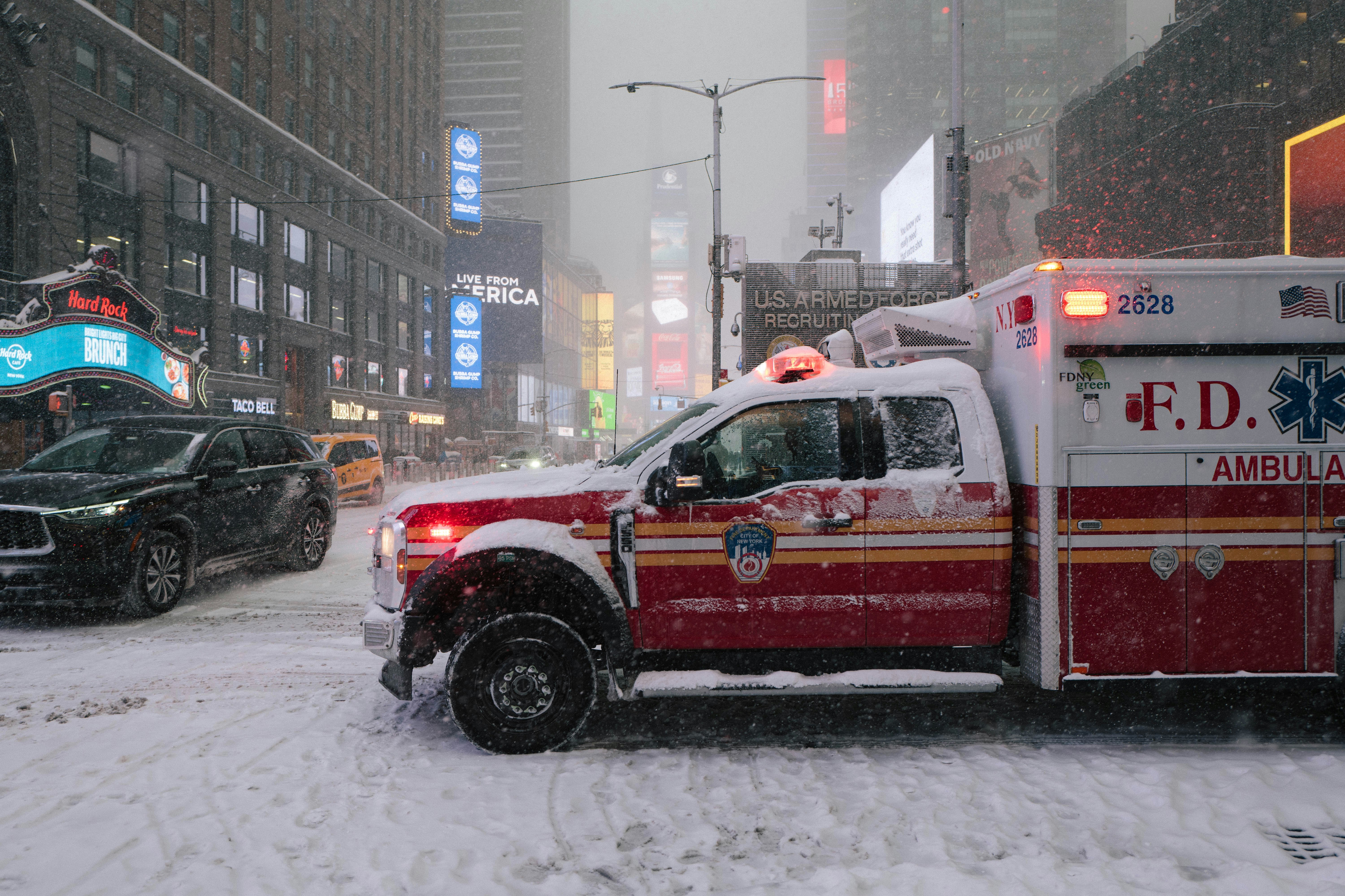 Ambulance driving through a snowy city street.
