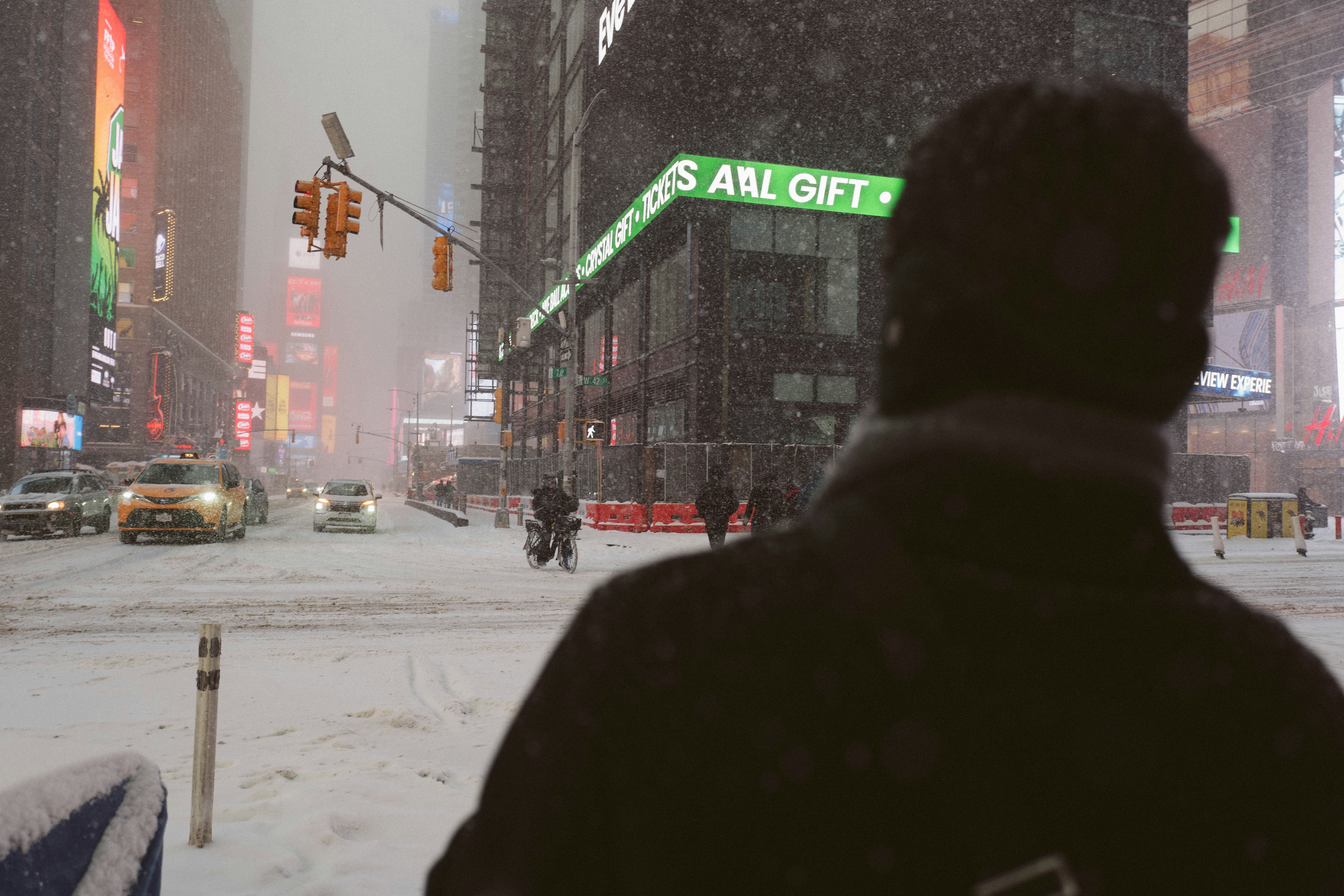 Person watches snow fall in a city street.