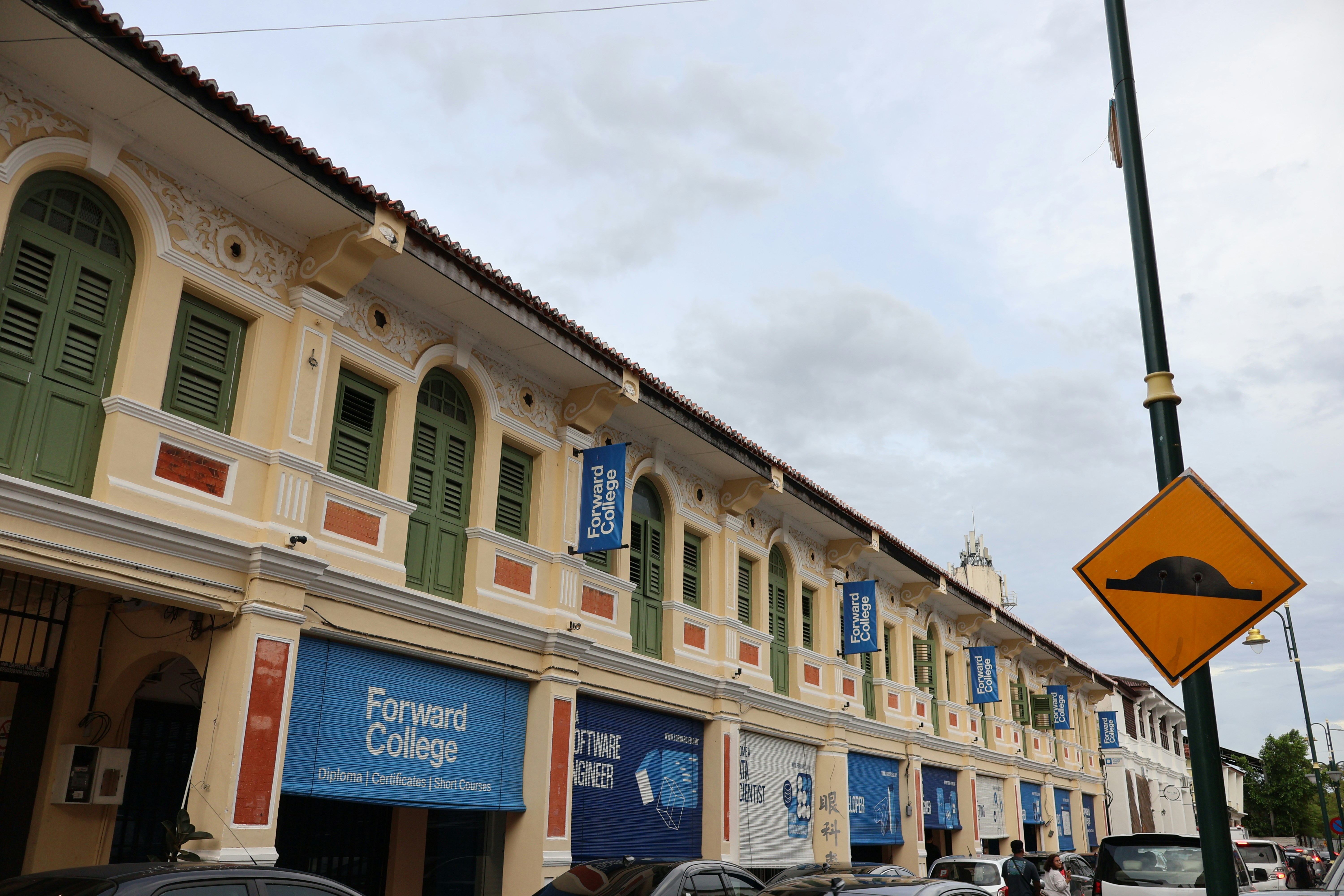 Row of old buildings with shops and college signs.