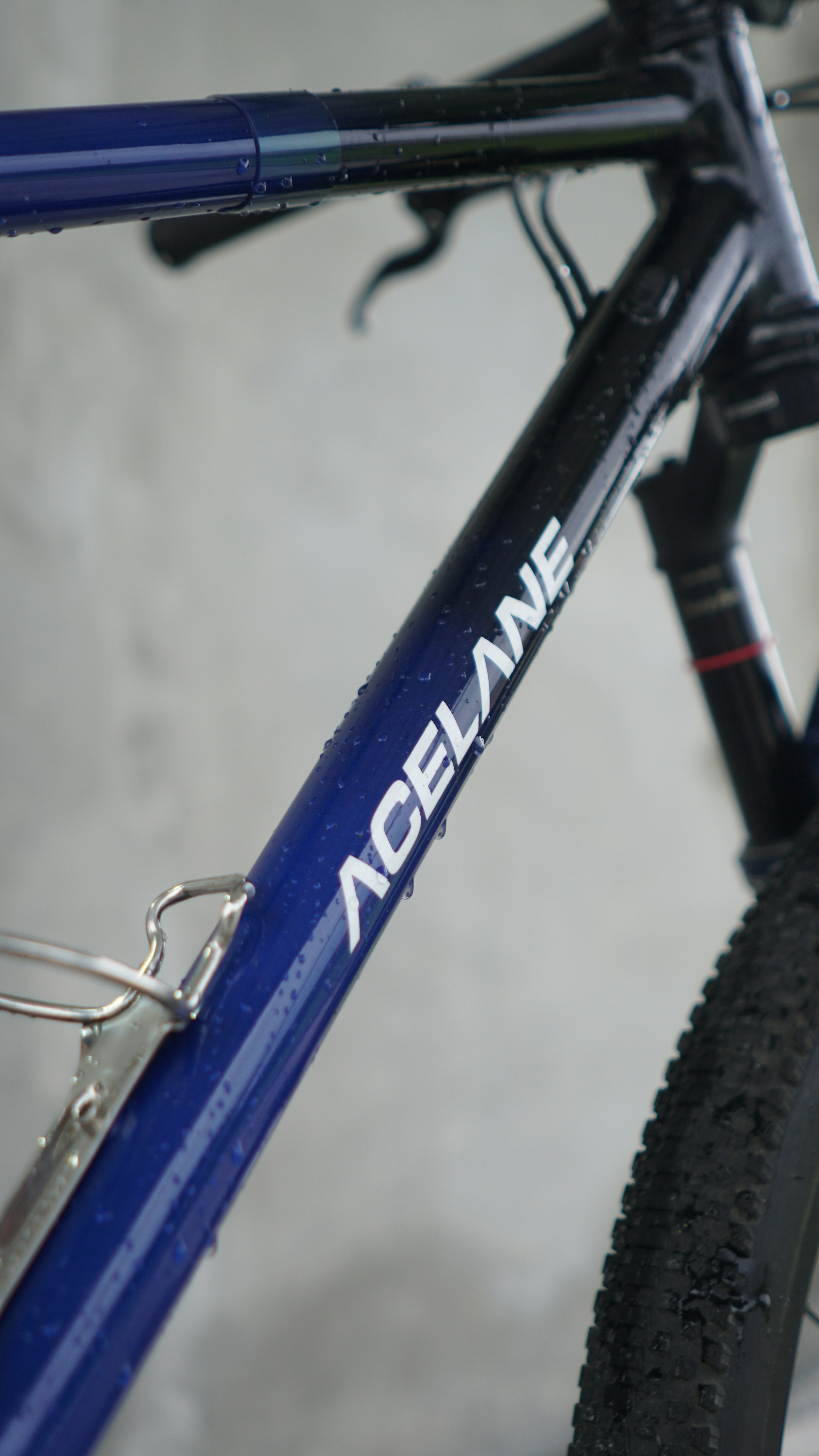 Close-up of a blue bicycle frame with water droplets.