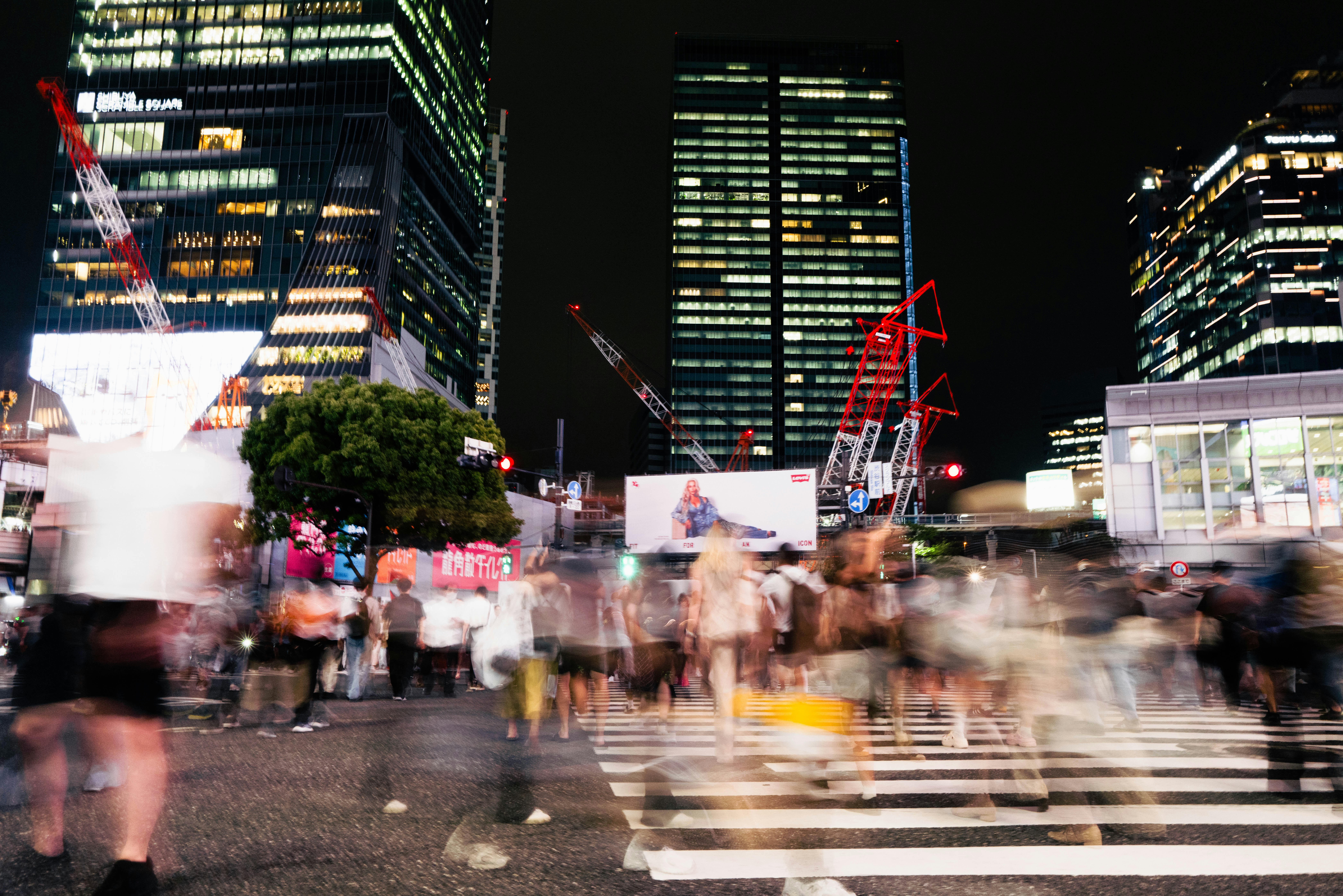 Busy city street at night with blurred pedestrians crossing pedestrians