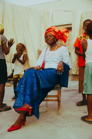 Woman in traditional attire sits surrounded by children.
