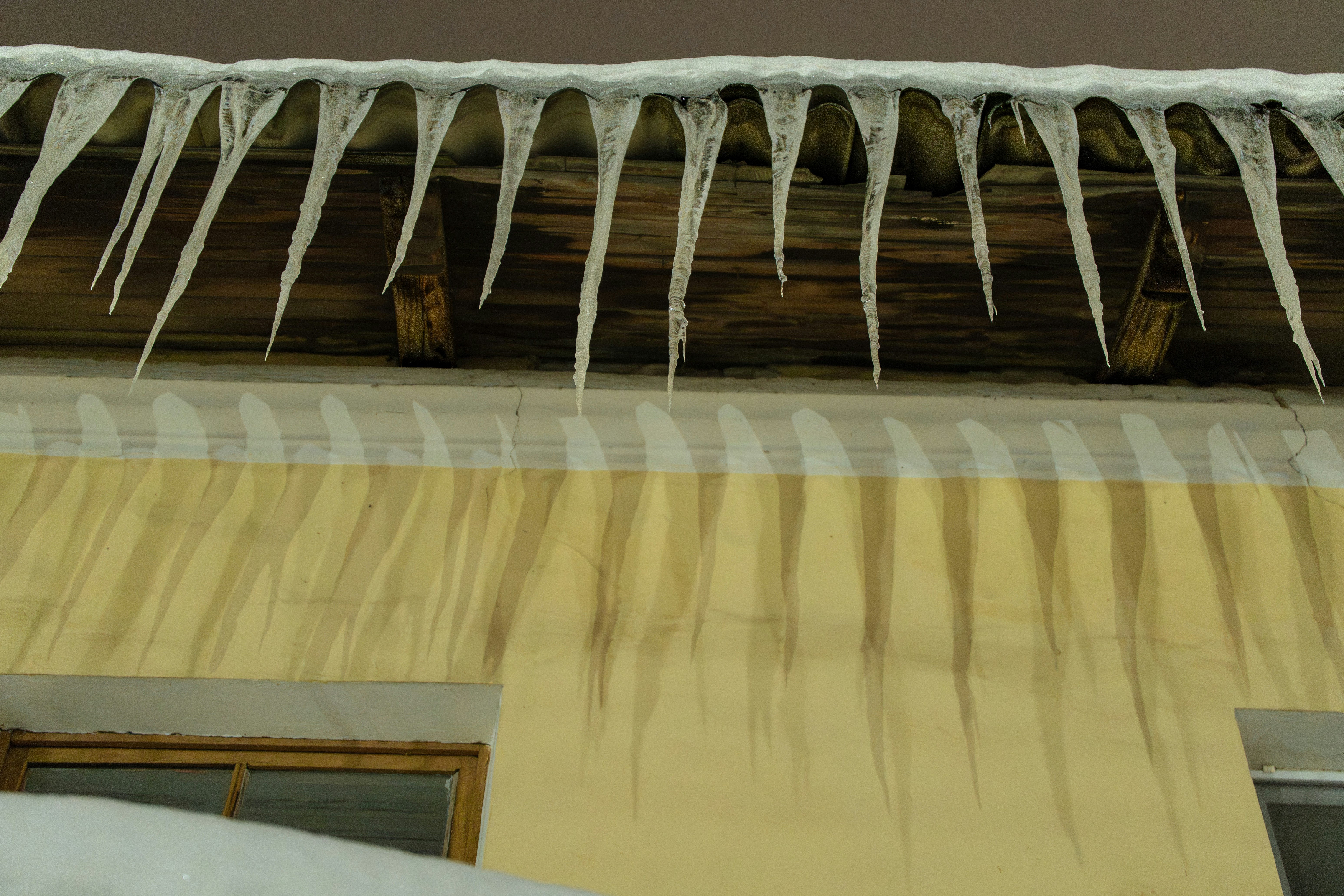 Icicles hanging from a wooden roof edge.