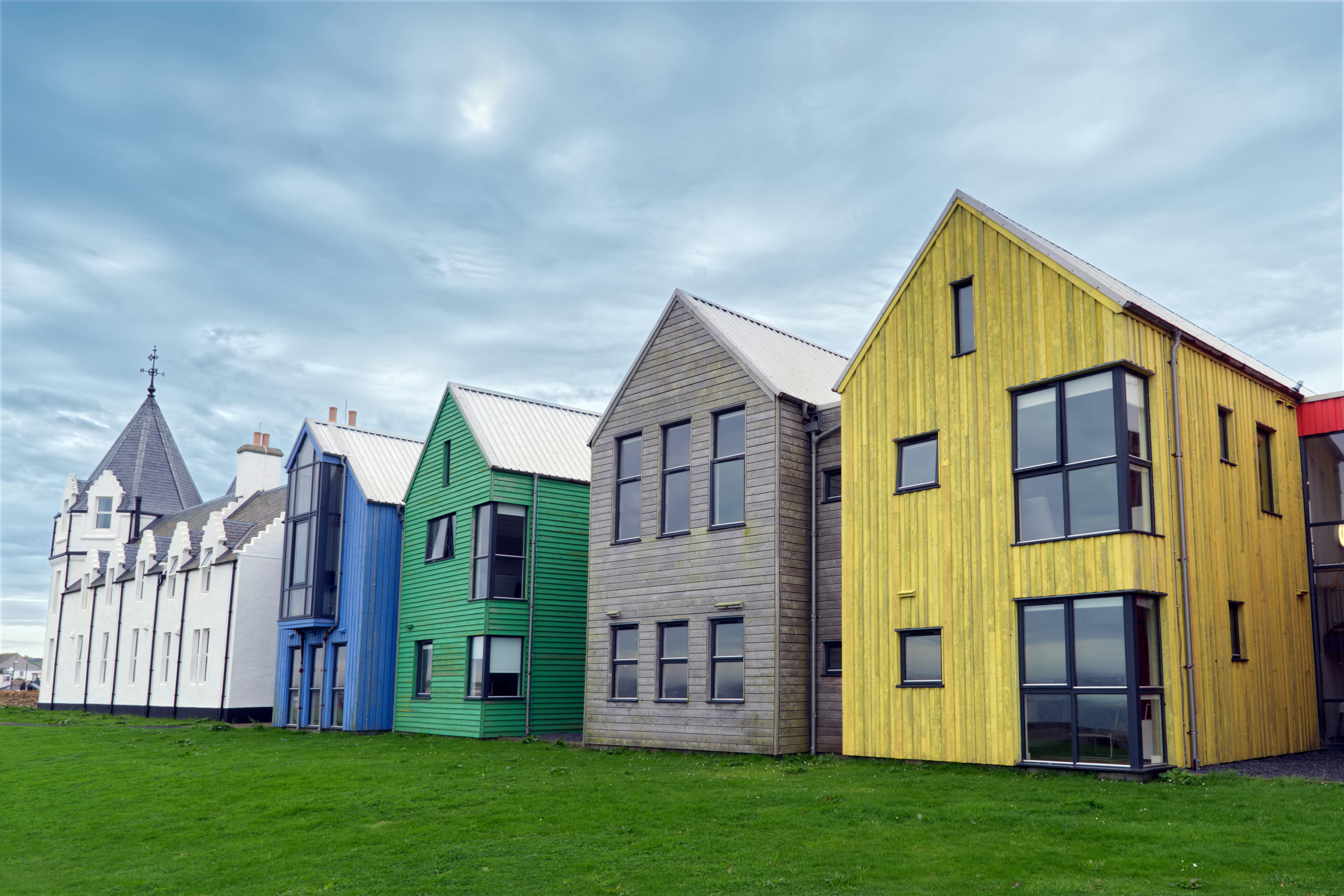 Colorful modern houses lined up on a grassy hill.