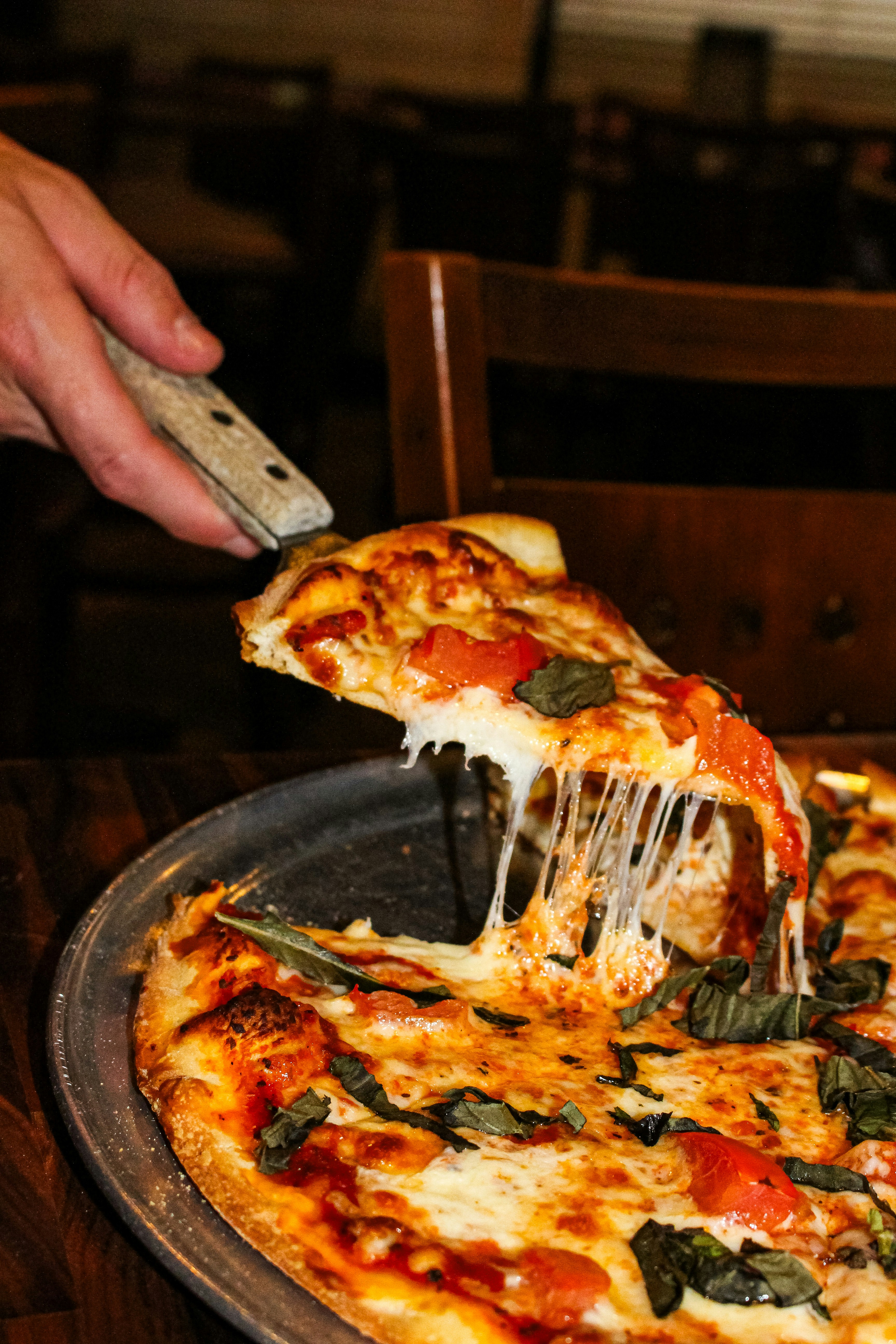 A slice of pizza with melted cheese being lifted
