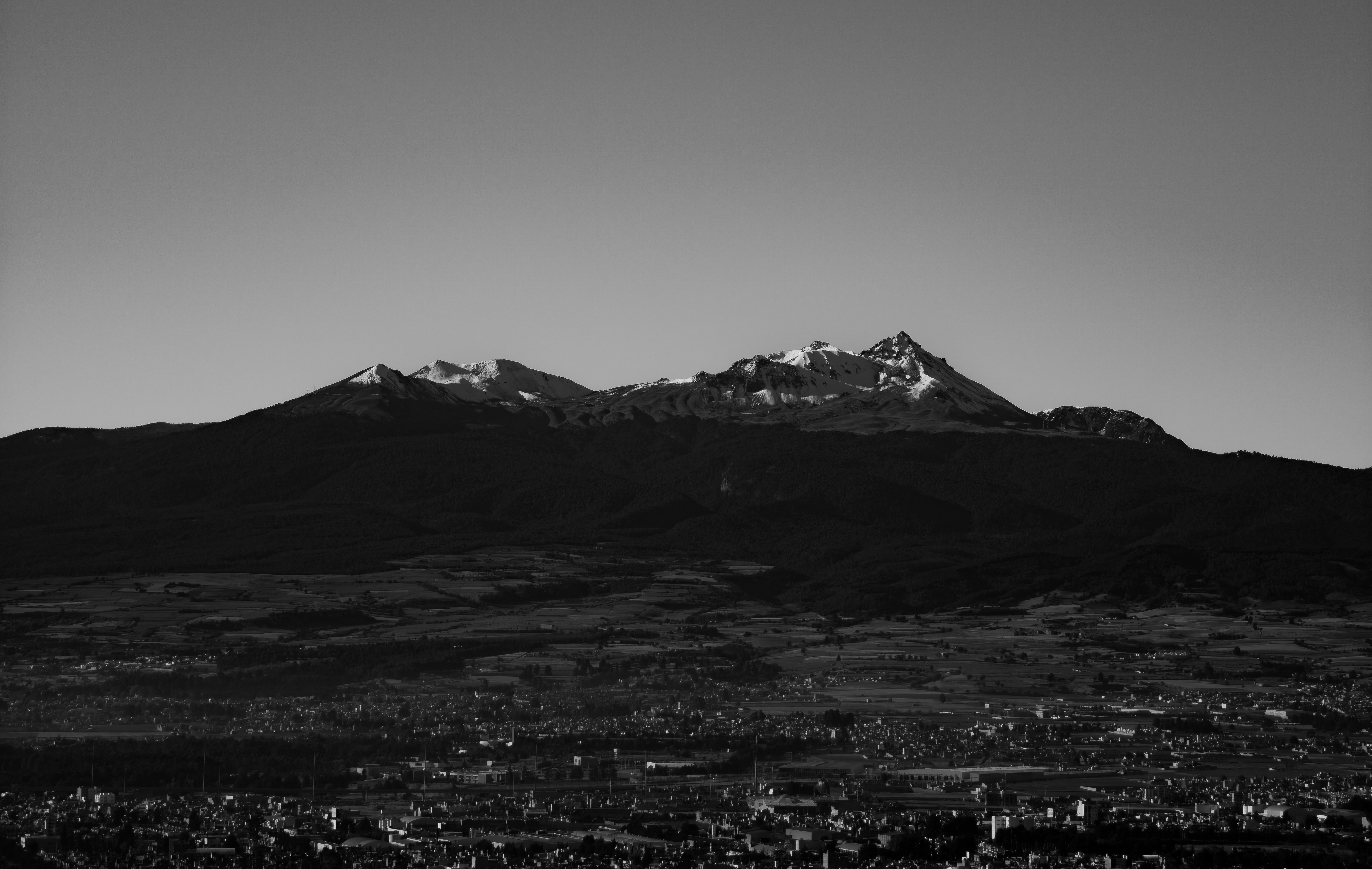 Des montagnes enneigées s’élèvent au-dessus d’une ville lointaine.