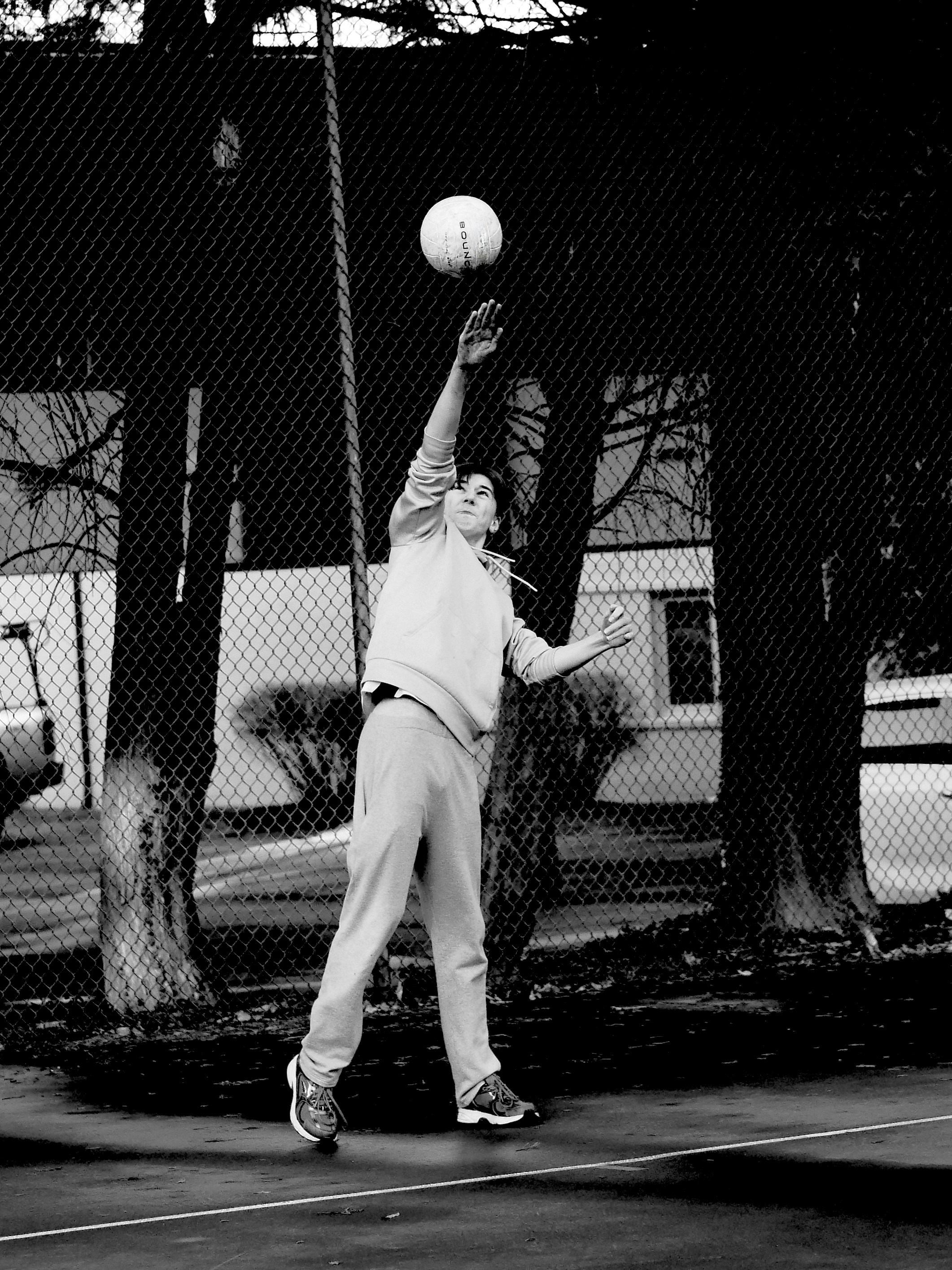 Young man playing volleyball outdoors near a fence.
