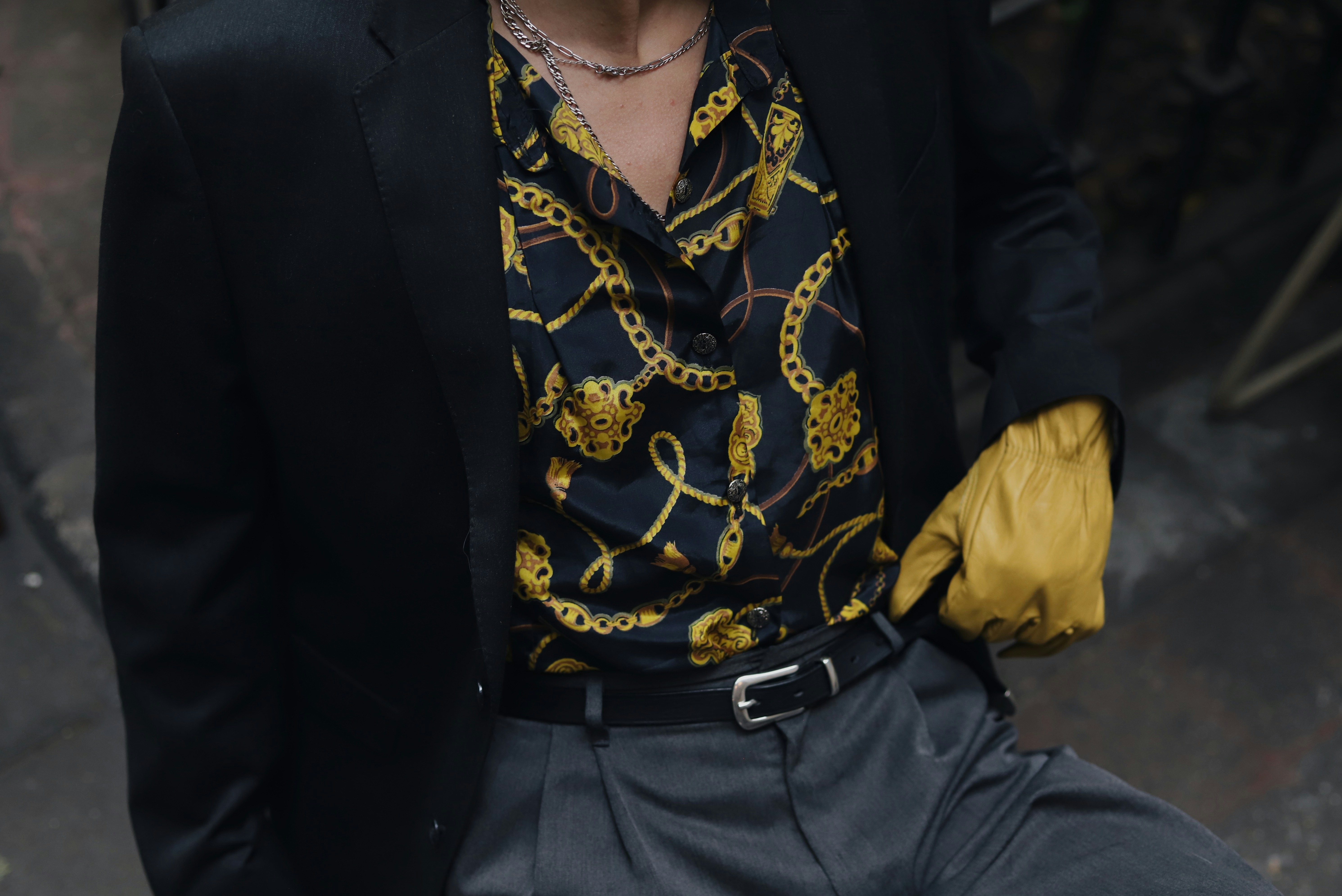 Man in black blazer and patterned shirt with yellow glove