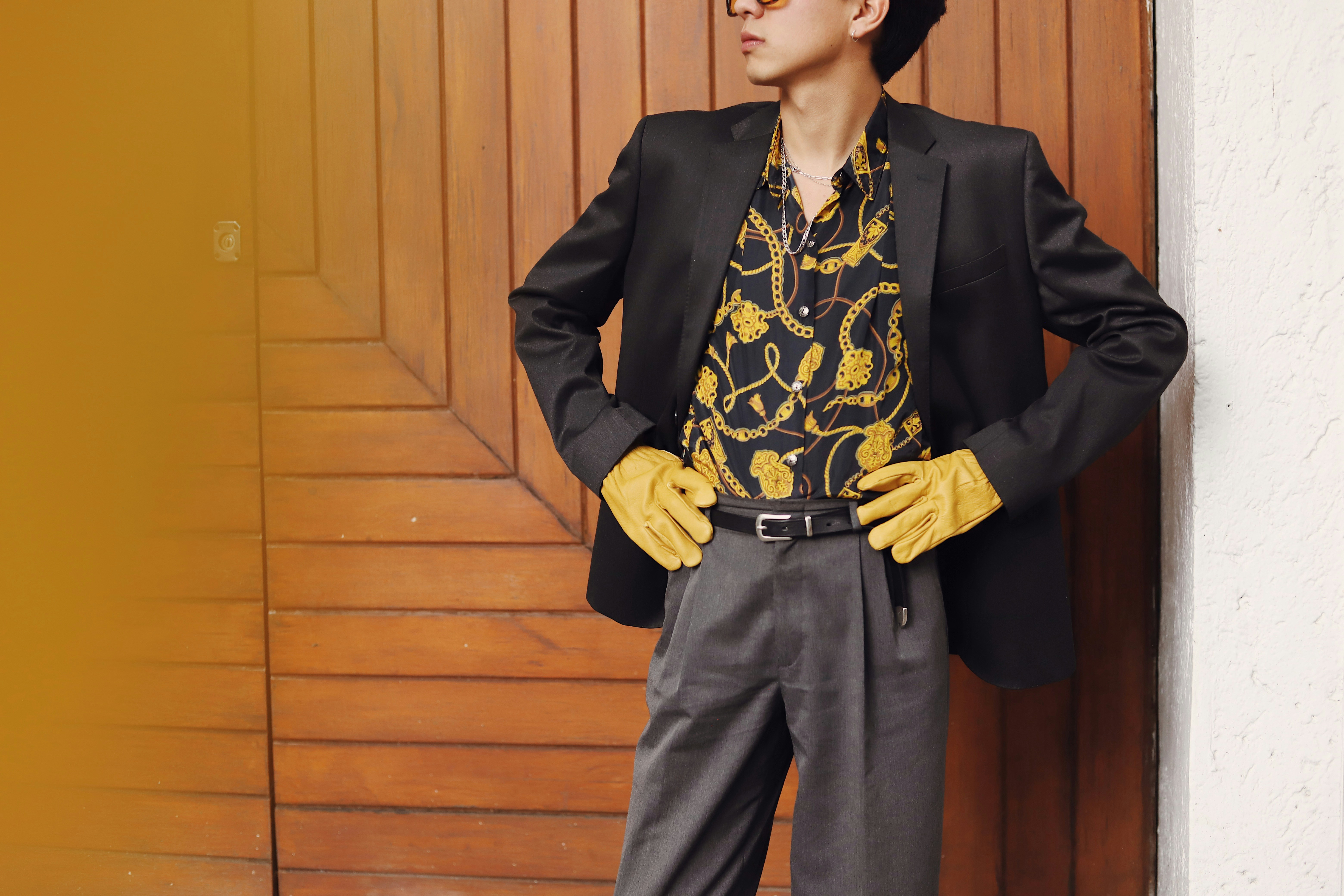 Man in stylish suit and gloves poses confidently.