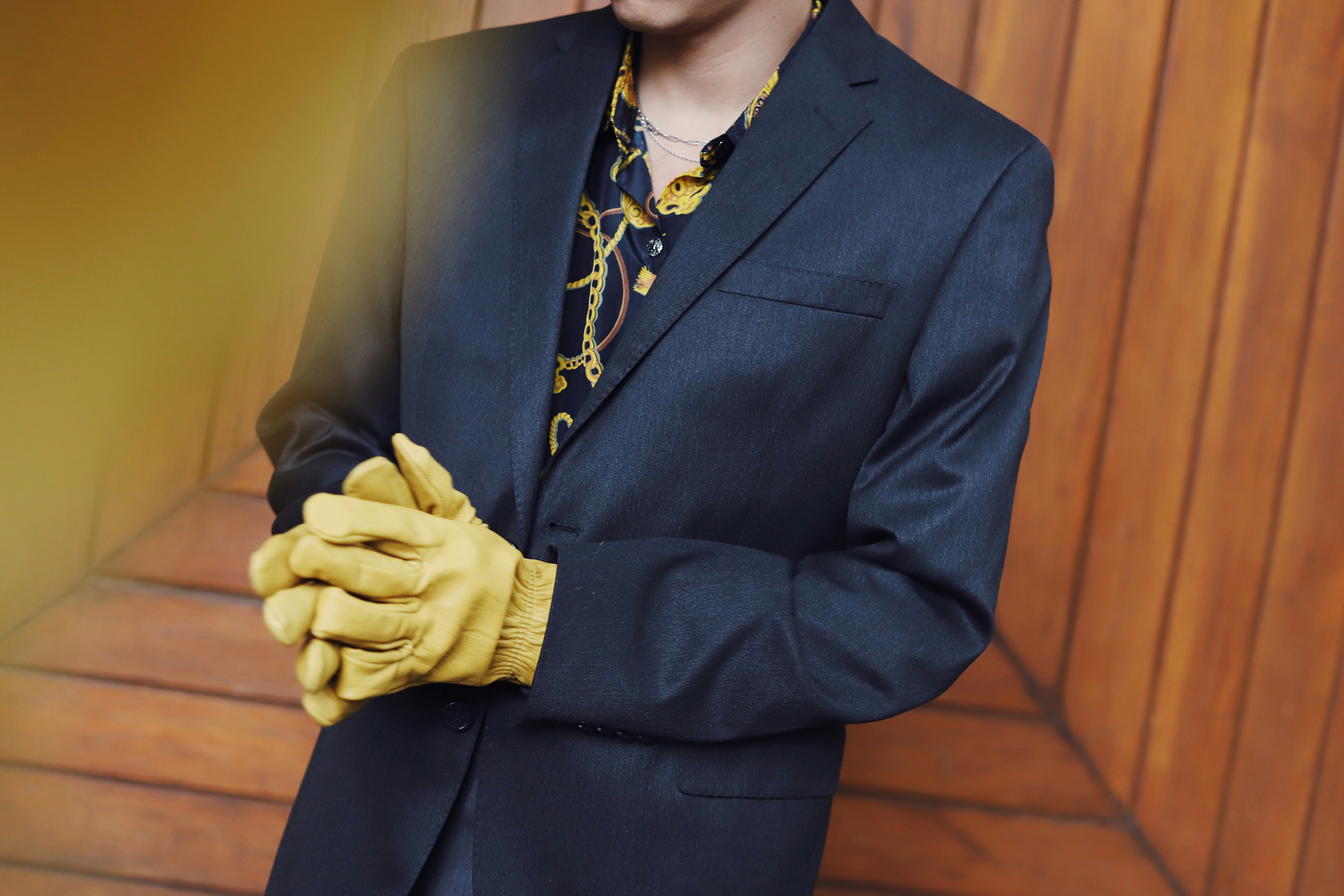 Man in suit and yellow gloves clasped hands
