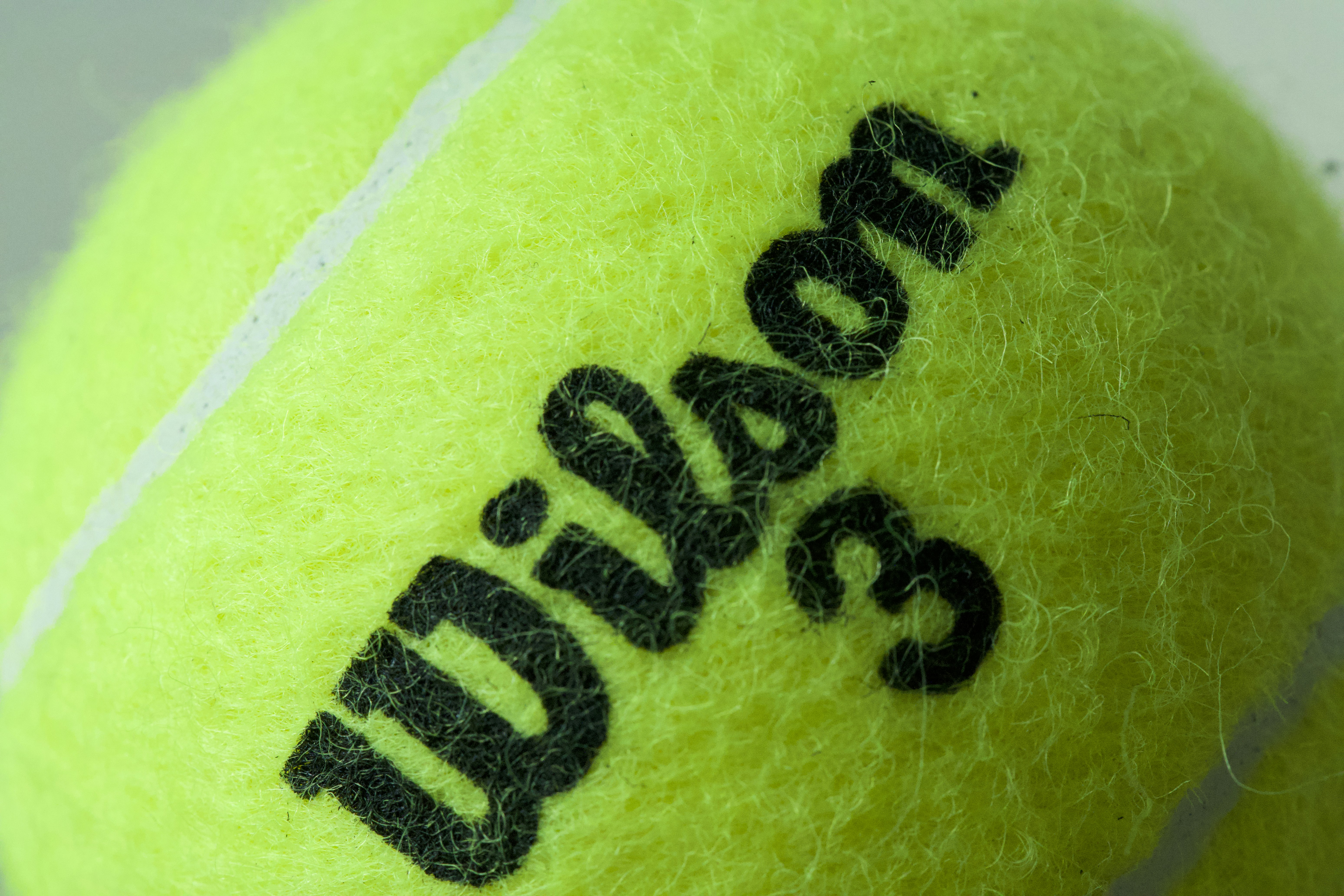 Close-up of a neon yellow tennis ball with wilson logo.