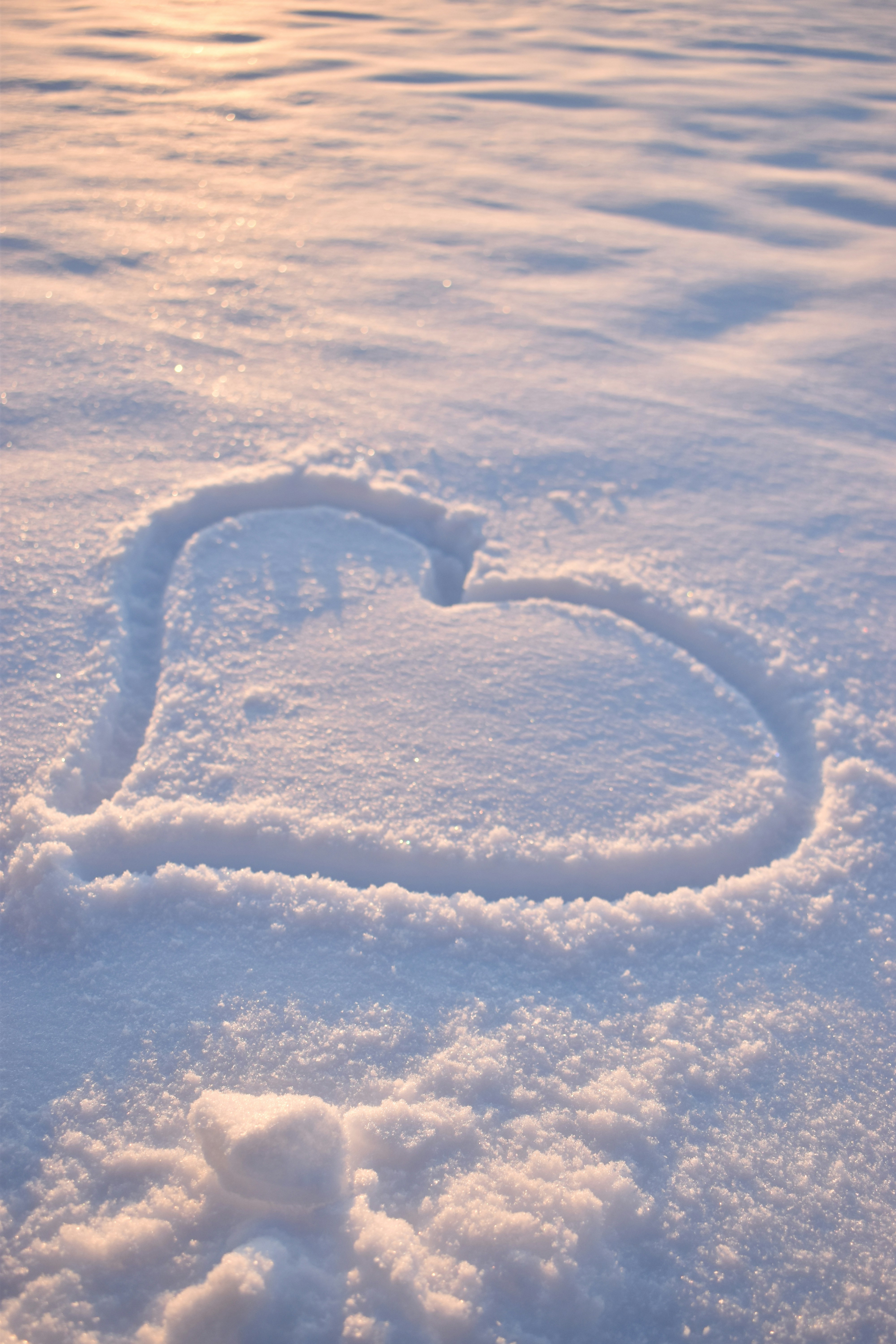 Heart drawn in fresh snow at sunset