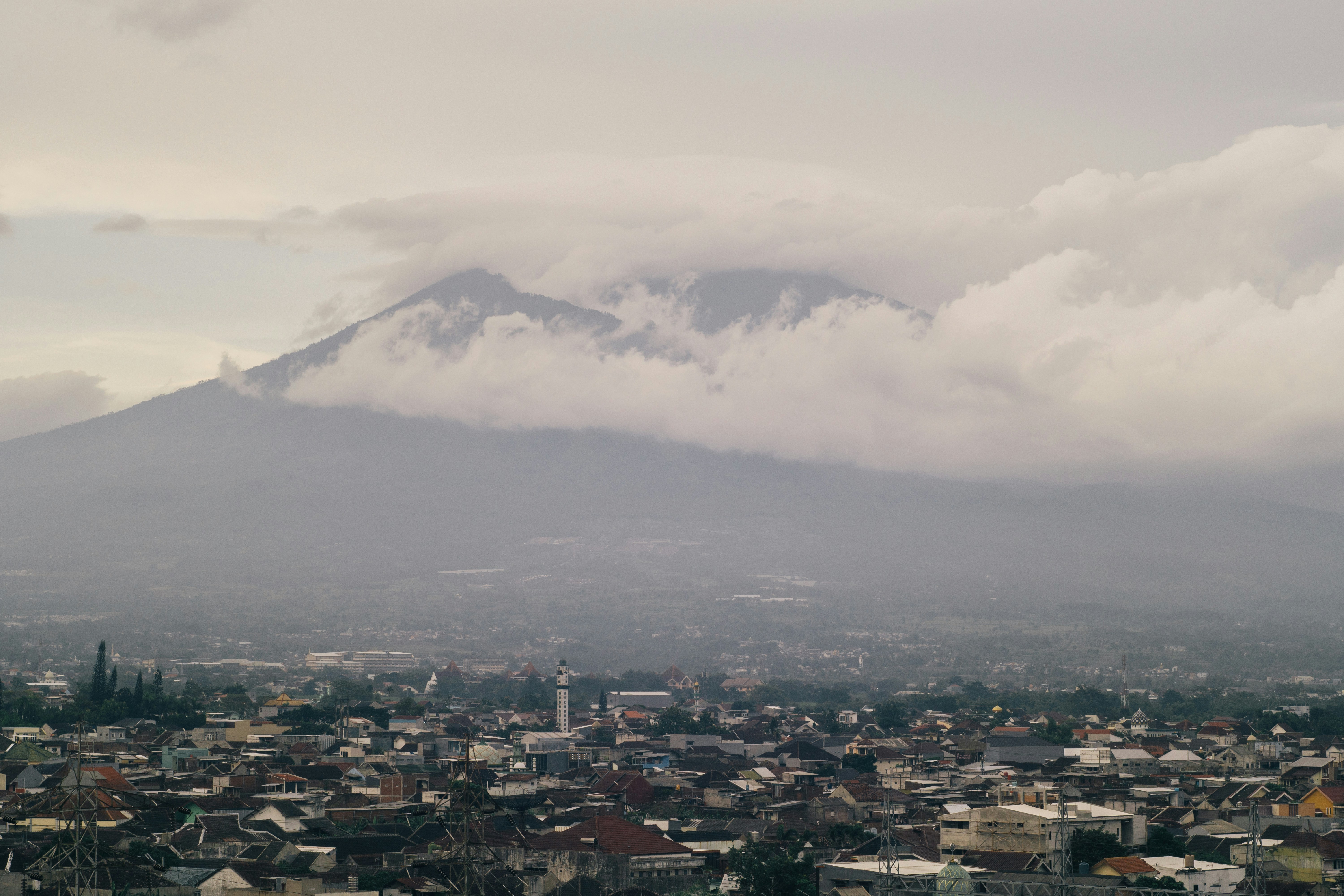 Mountain peak shrouded in clouds above a town