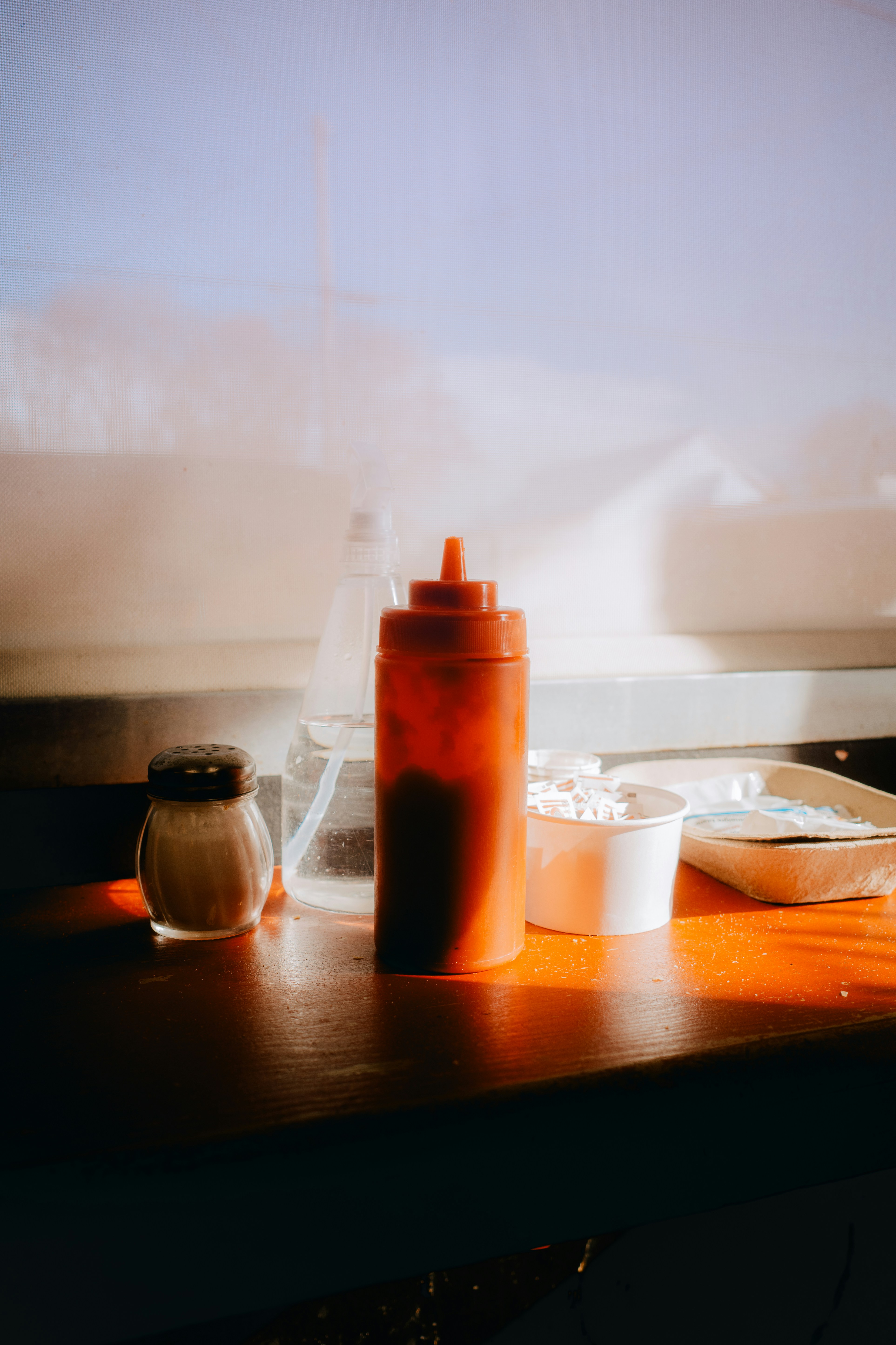 Condiment bottles and containers on a wooden surface.