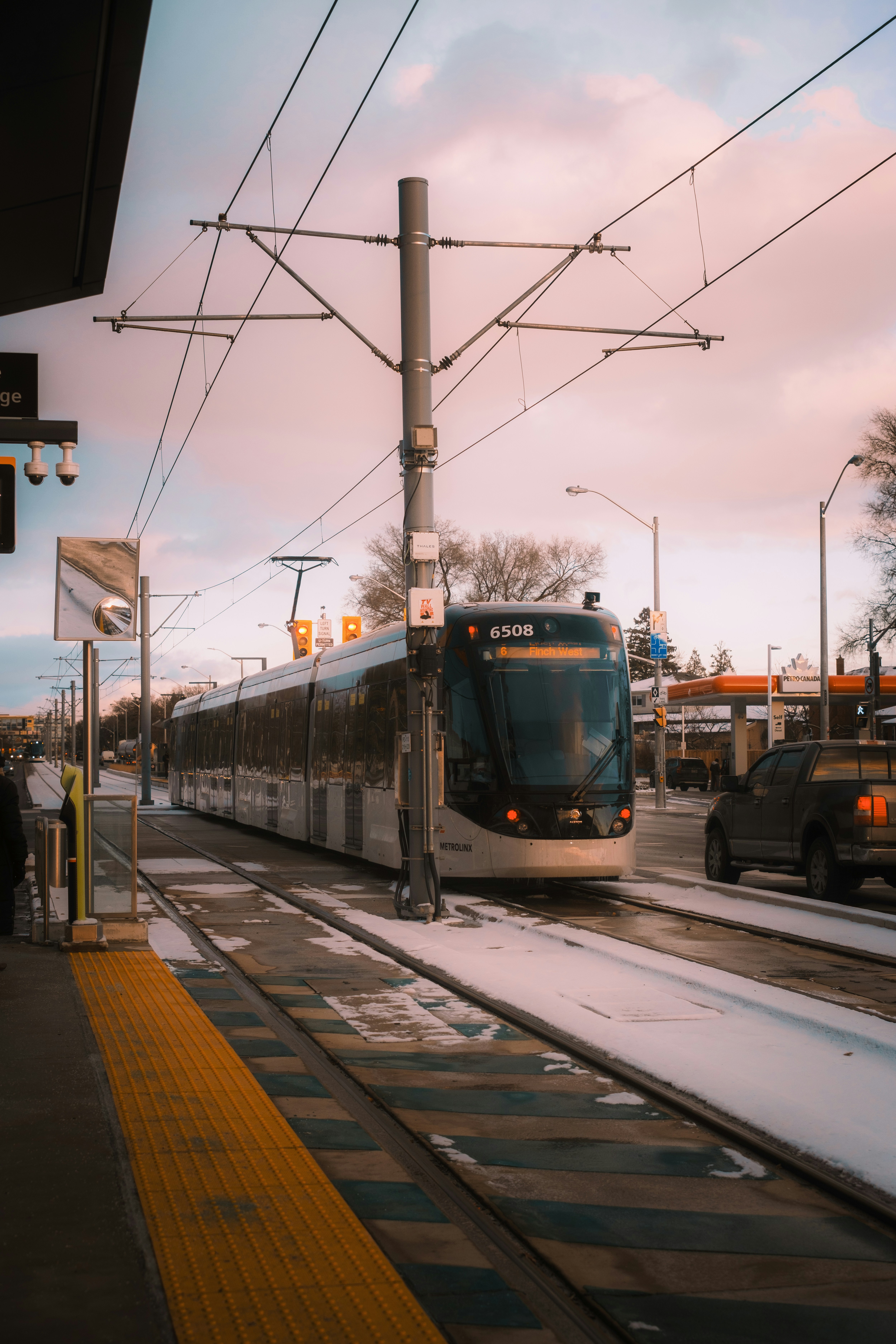 A modern tram on tracks with snow on the ground.