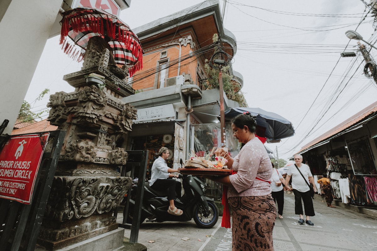 Woman carrying offerings in front of ornate temple entrance