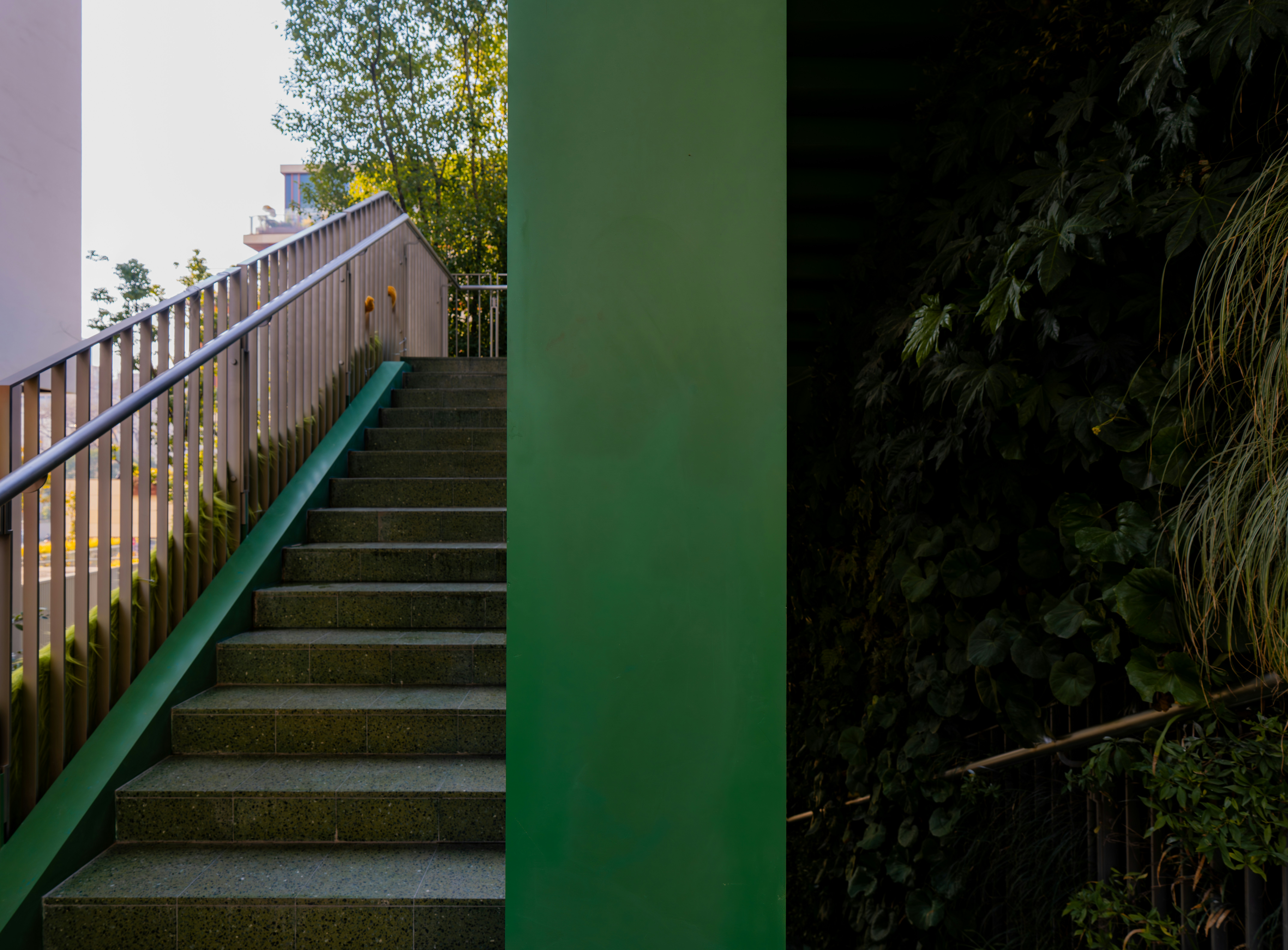 Escada externa com corrimãos de metal e destaque verde