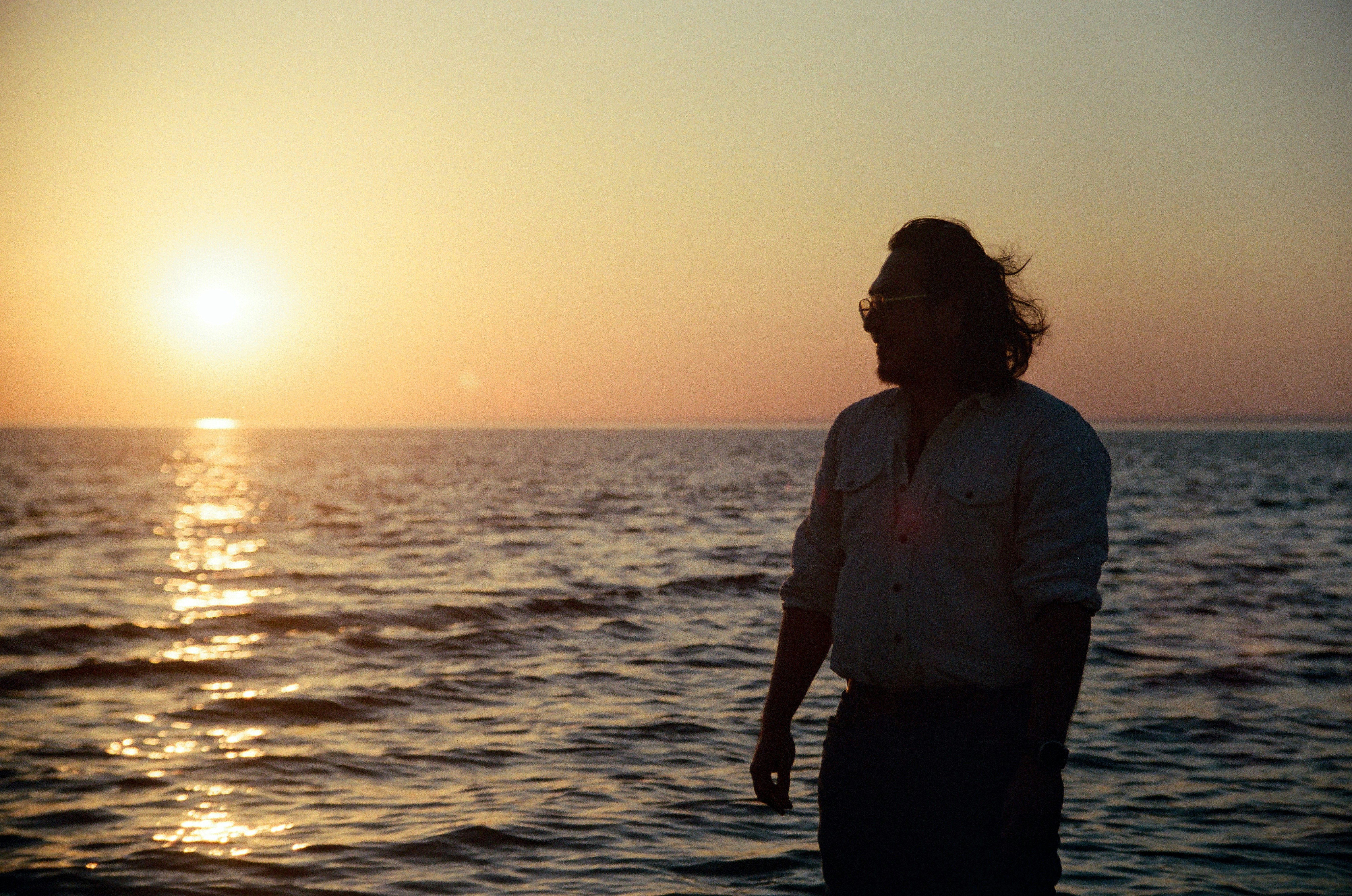 Mann abzeichnet sich vor einem goldenen Meeresuntergang