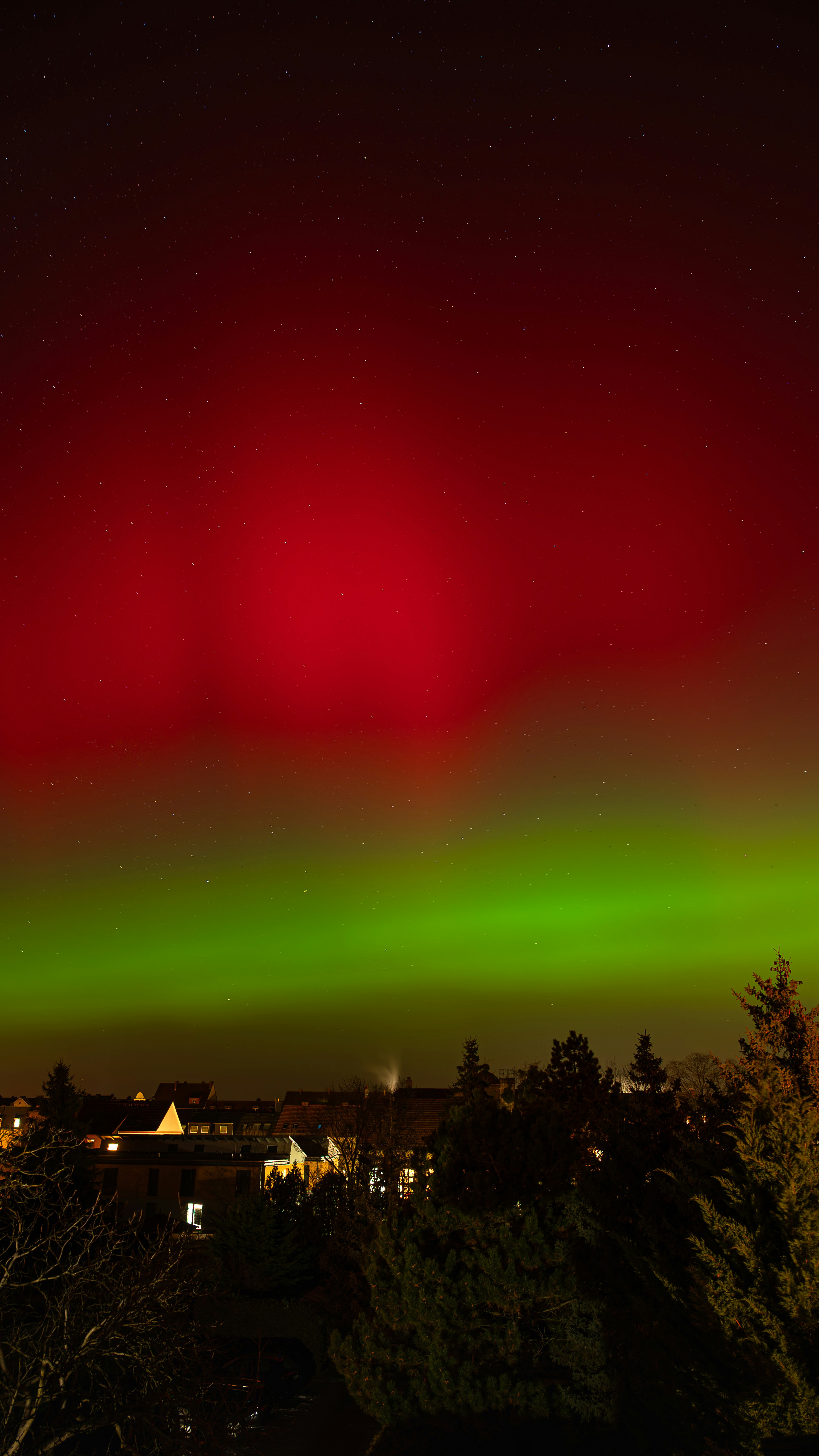 Aurora boreale rossa e verde sopra una città di notte