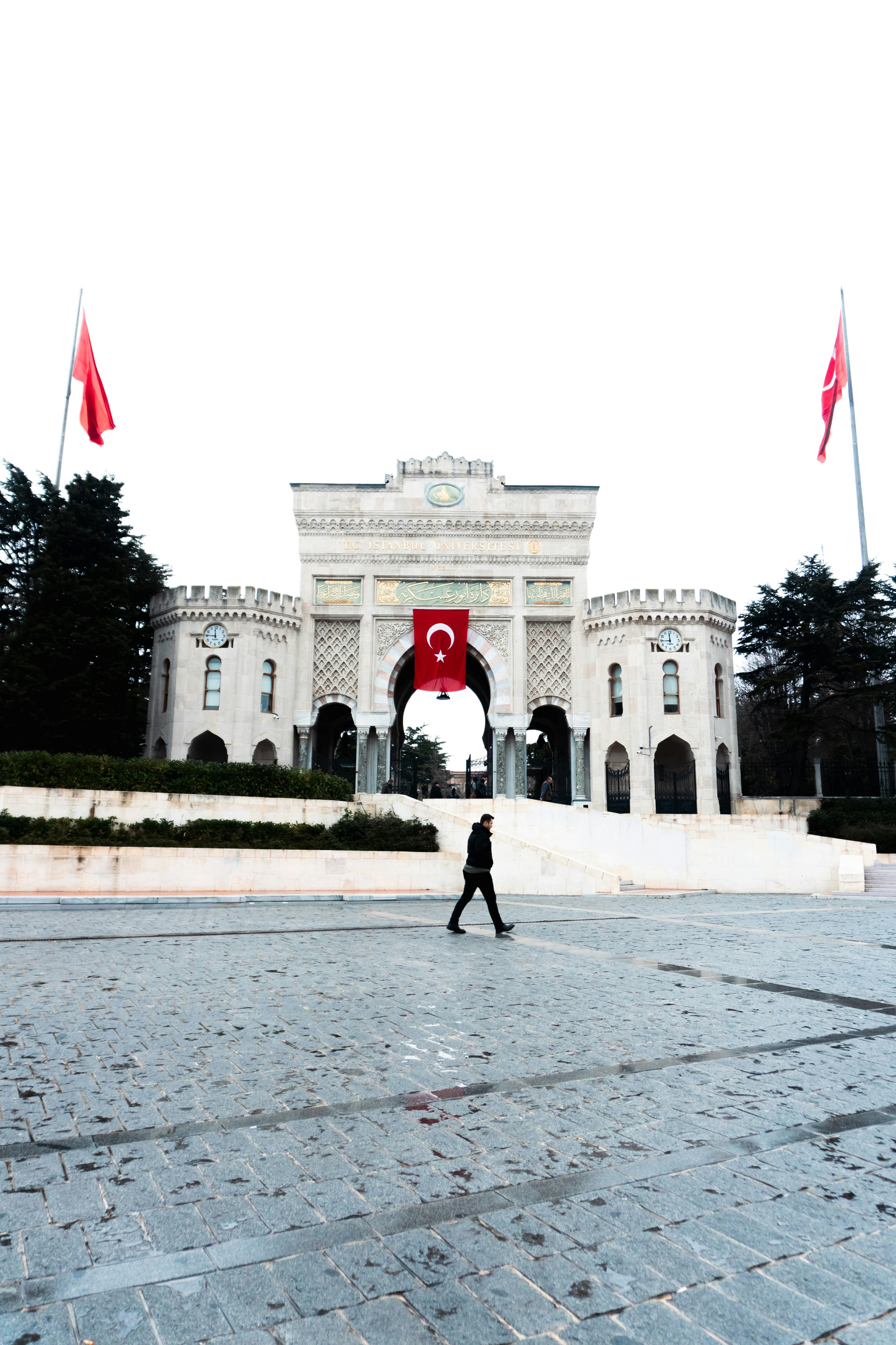Una persona cammina davanti all'ingresso principale dell'università con bandiere