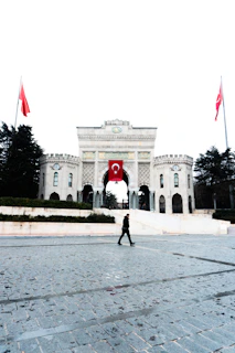 Person walks in front of grand university entrance with flags