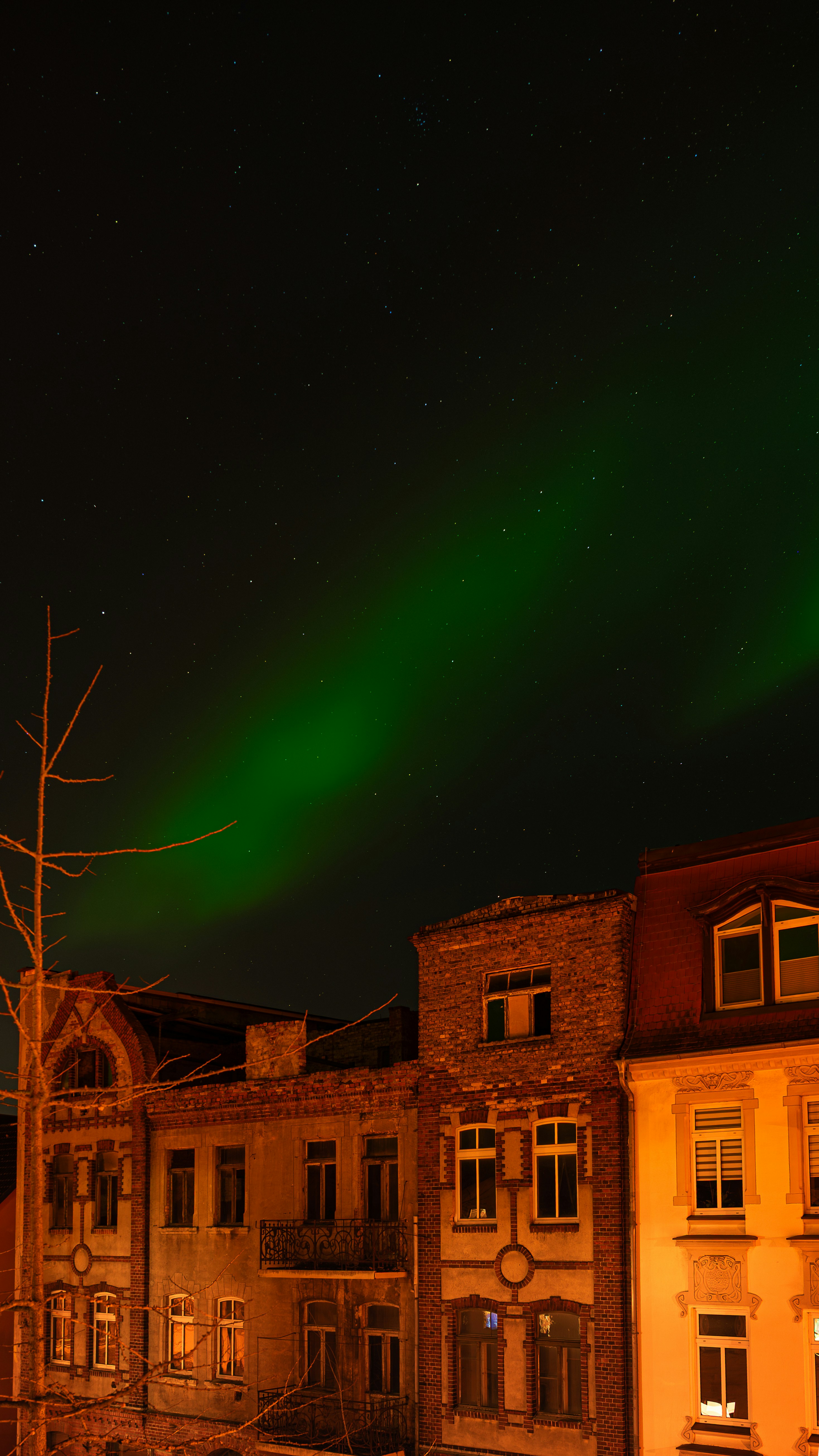 Aurora boreale verde sopra edifici antichi di notte.