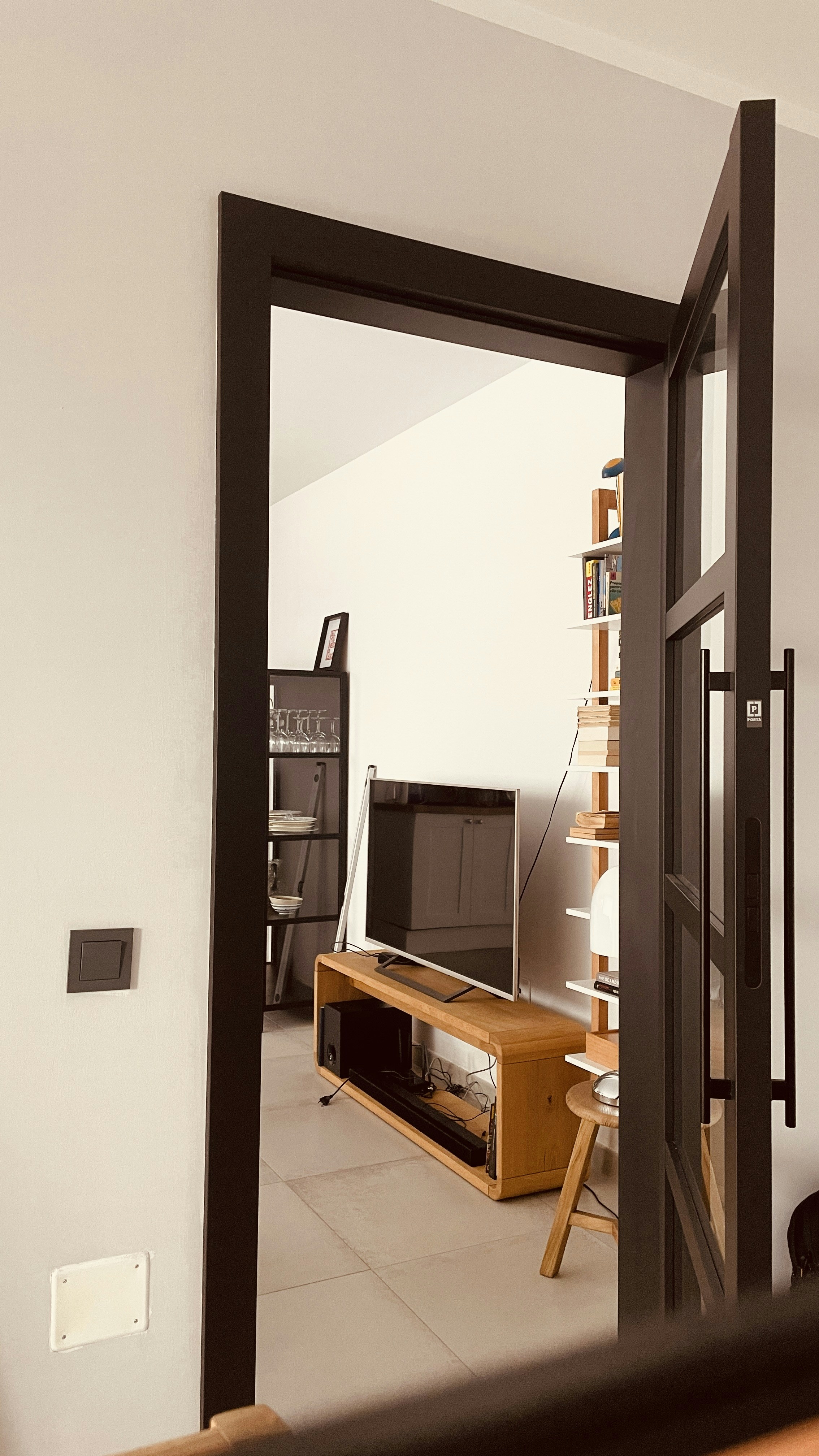 View through doorway to living room with TV and shelves