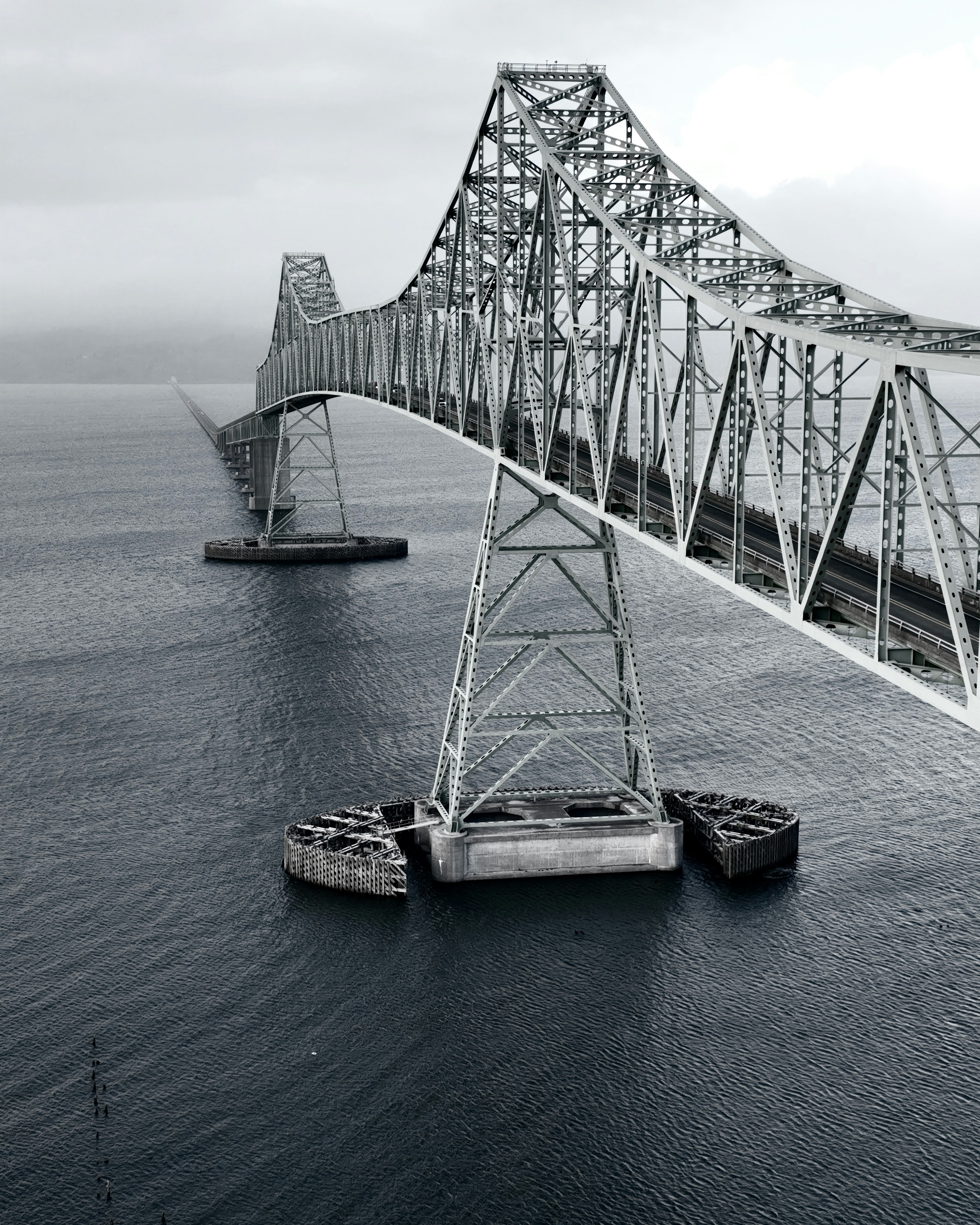 A large metal bridge spans over dark blue water.