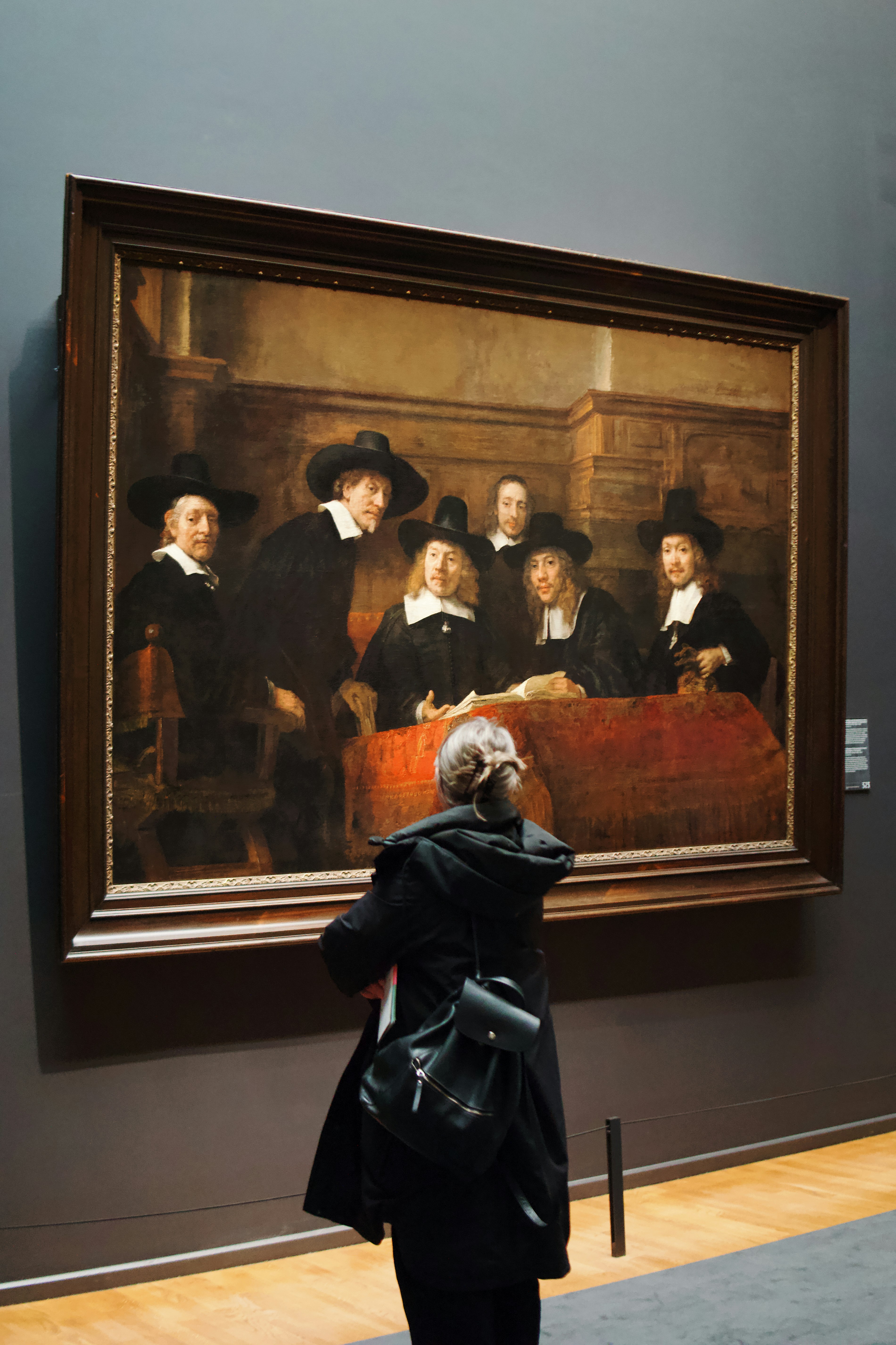 Personne inspectant un tableau ancien avec une loupe