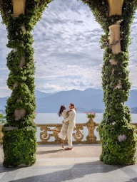 Couple embracing on a balcony overlooking a lake and mountains.