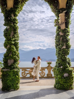 Couple embracing on a balcony overlooking a lake and mountains.