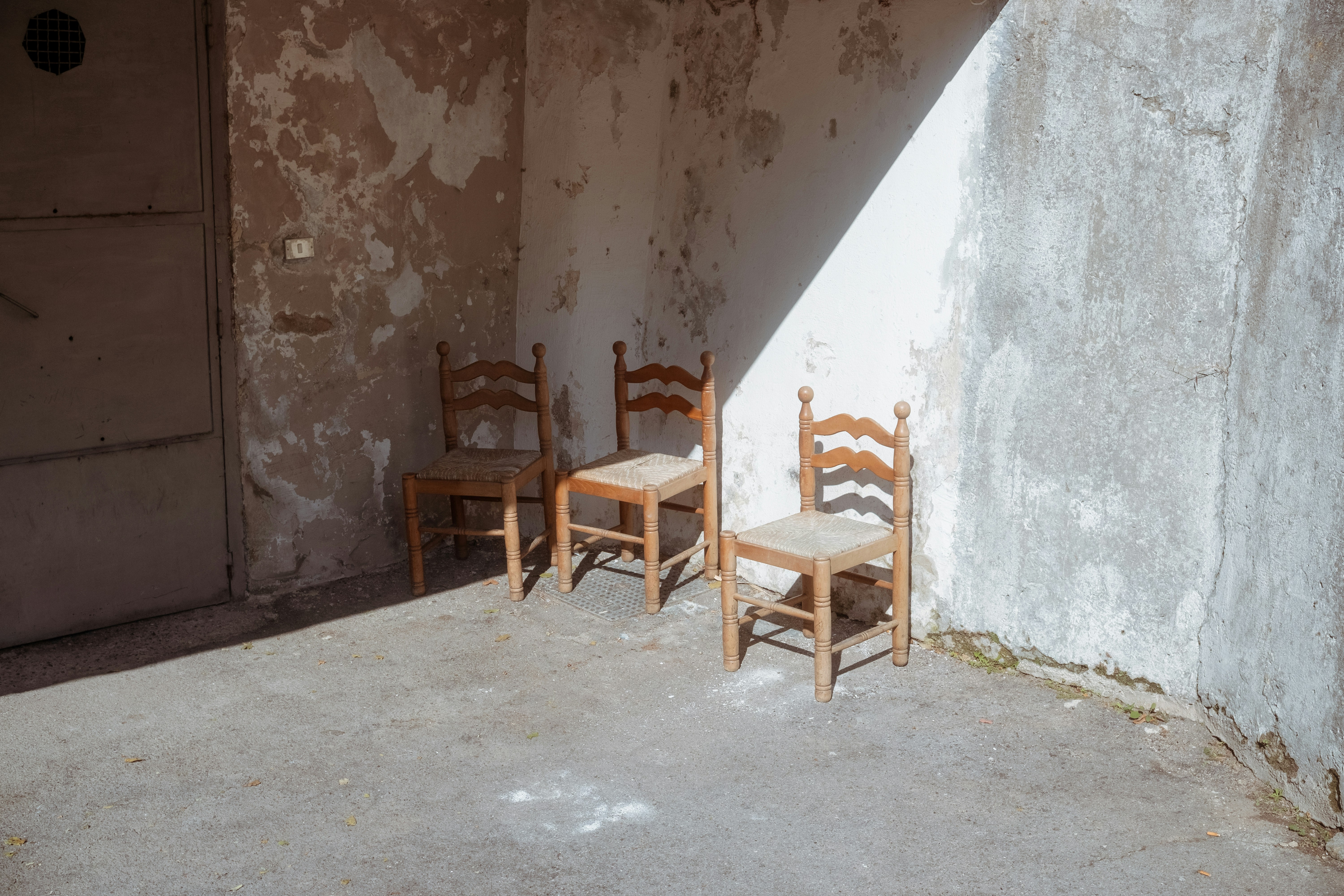 Drei Holzstühle in einer sonnenbeschienenen Ecke