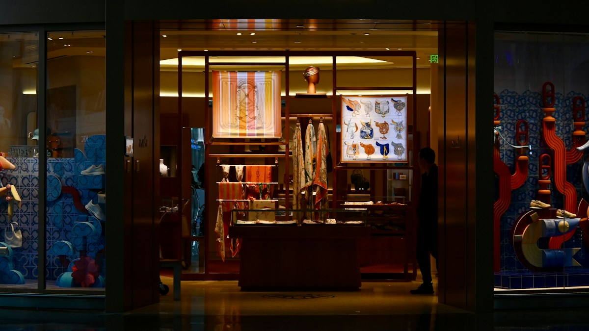 Vitrine éclairée d’une boutique de luxe la nuit, foulards et accessoires exposés