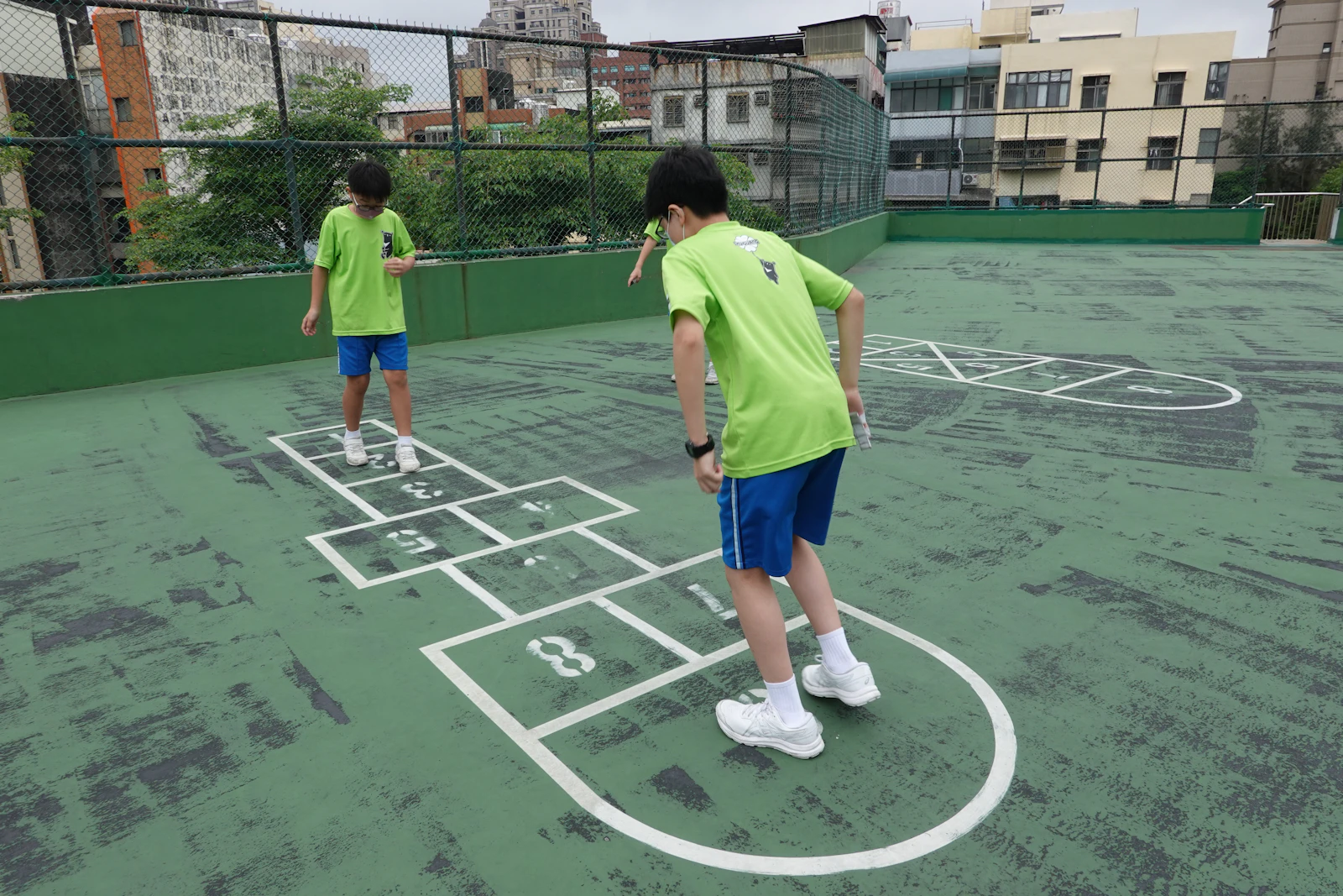 Two children playing hopscotch on the school court