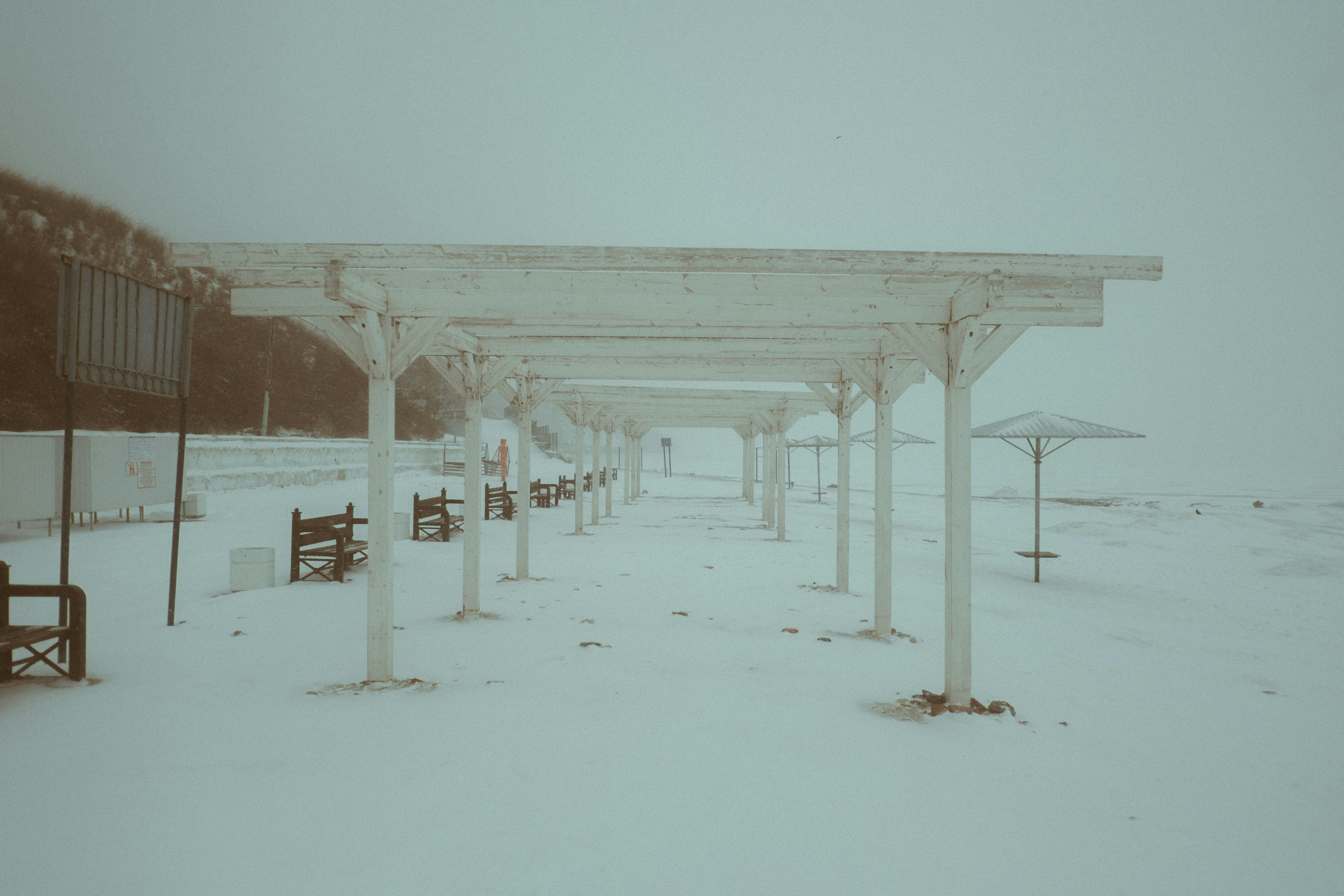 Pergola structure on a snowy beach with umbrellas
