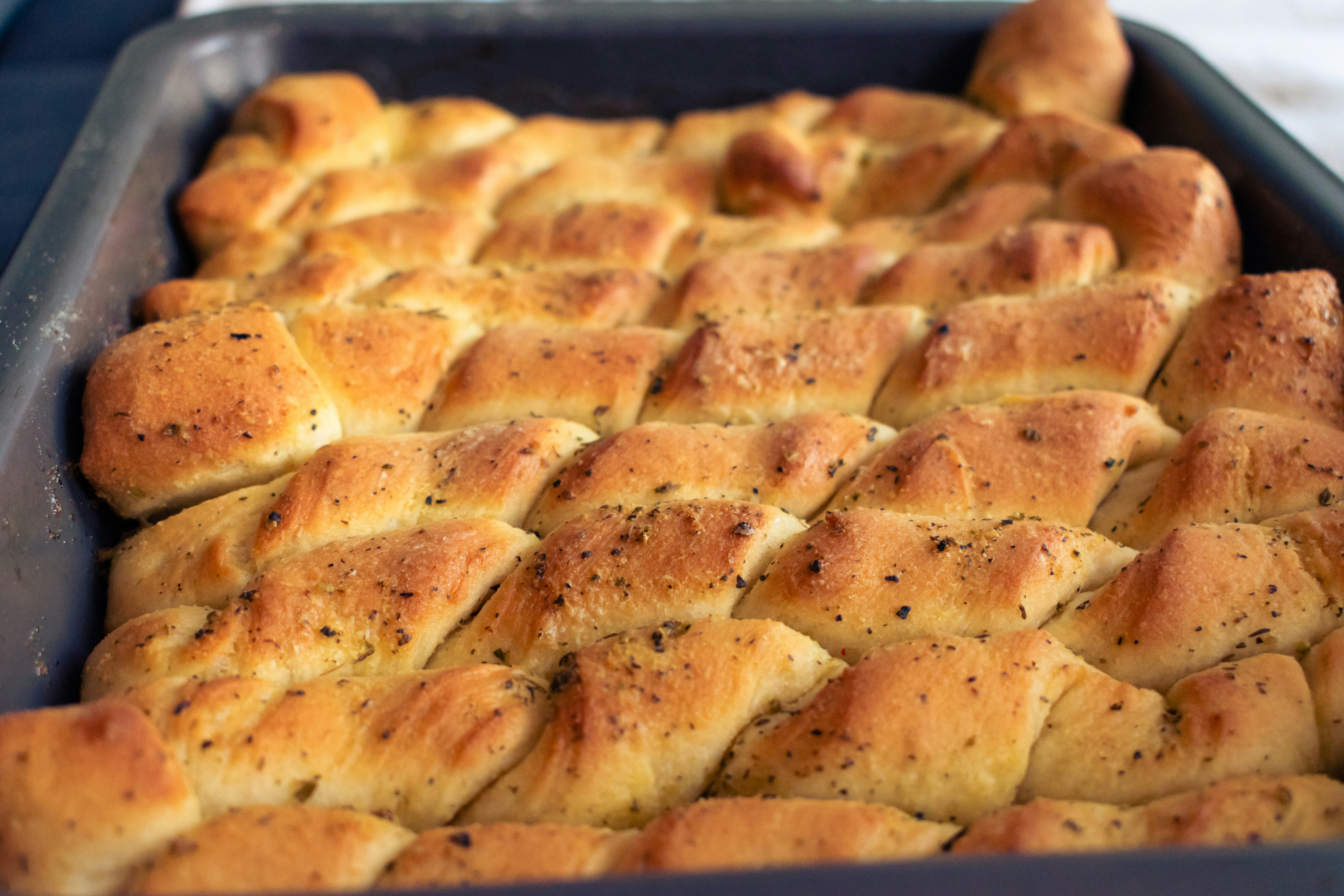 Des bâtonnets de pain dorés arrangés dans un plat de cuisson.