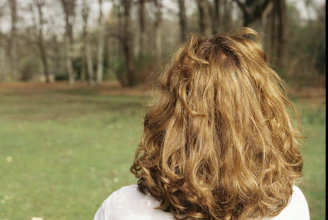 Woman with long curly blonde hair in a park.