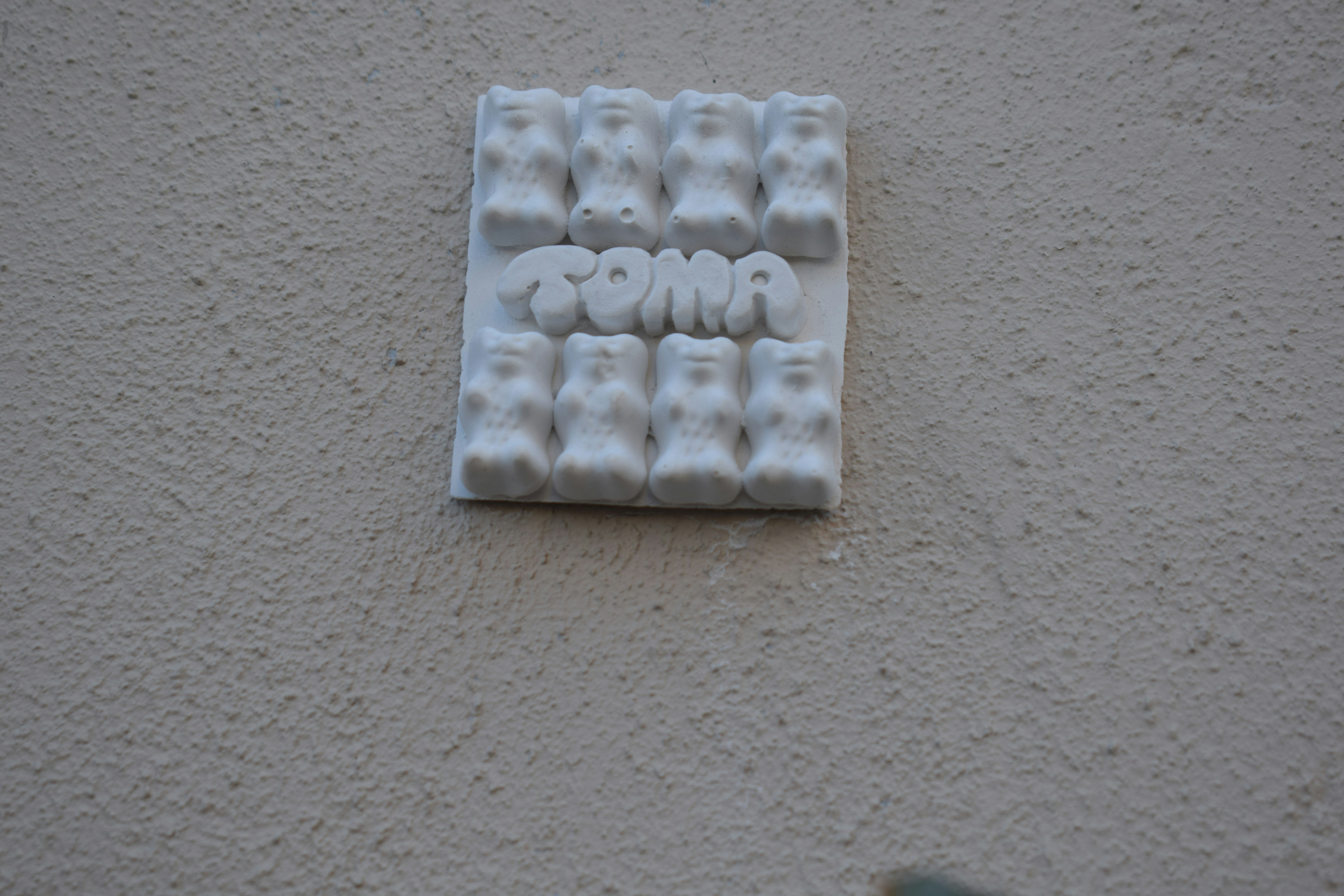 White gummy bears arranged on a textured wall