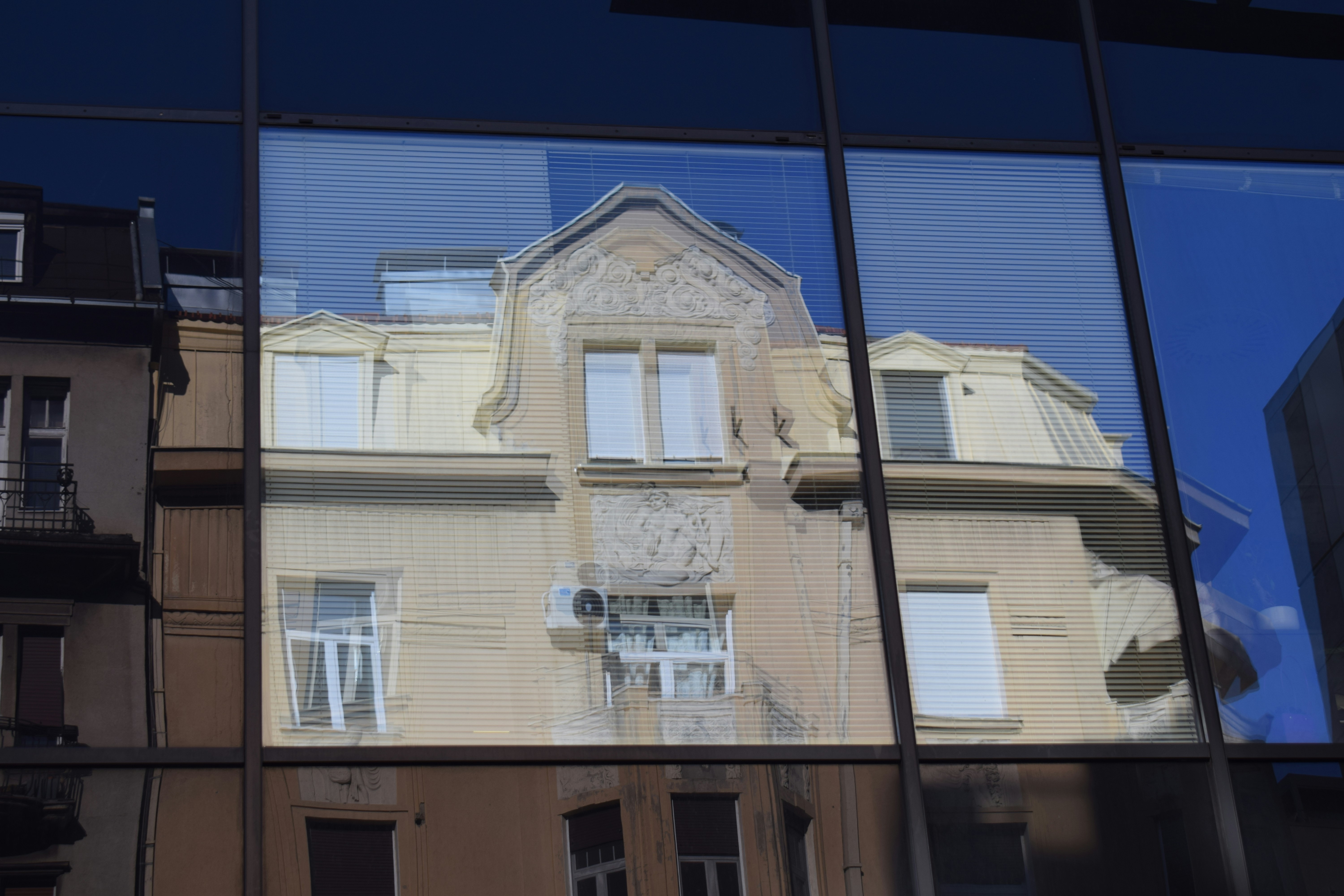 Le reflet d’un bâtiment sur une façade moderne en verre.