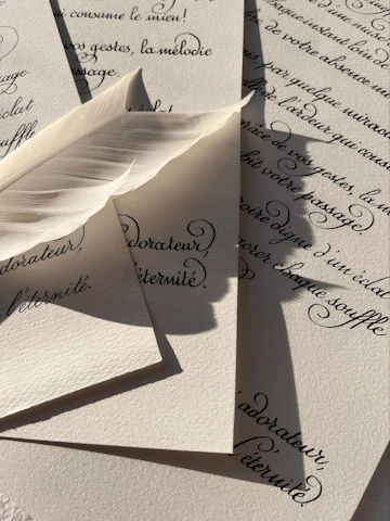 A white feather rests on handwritten calligraphy.