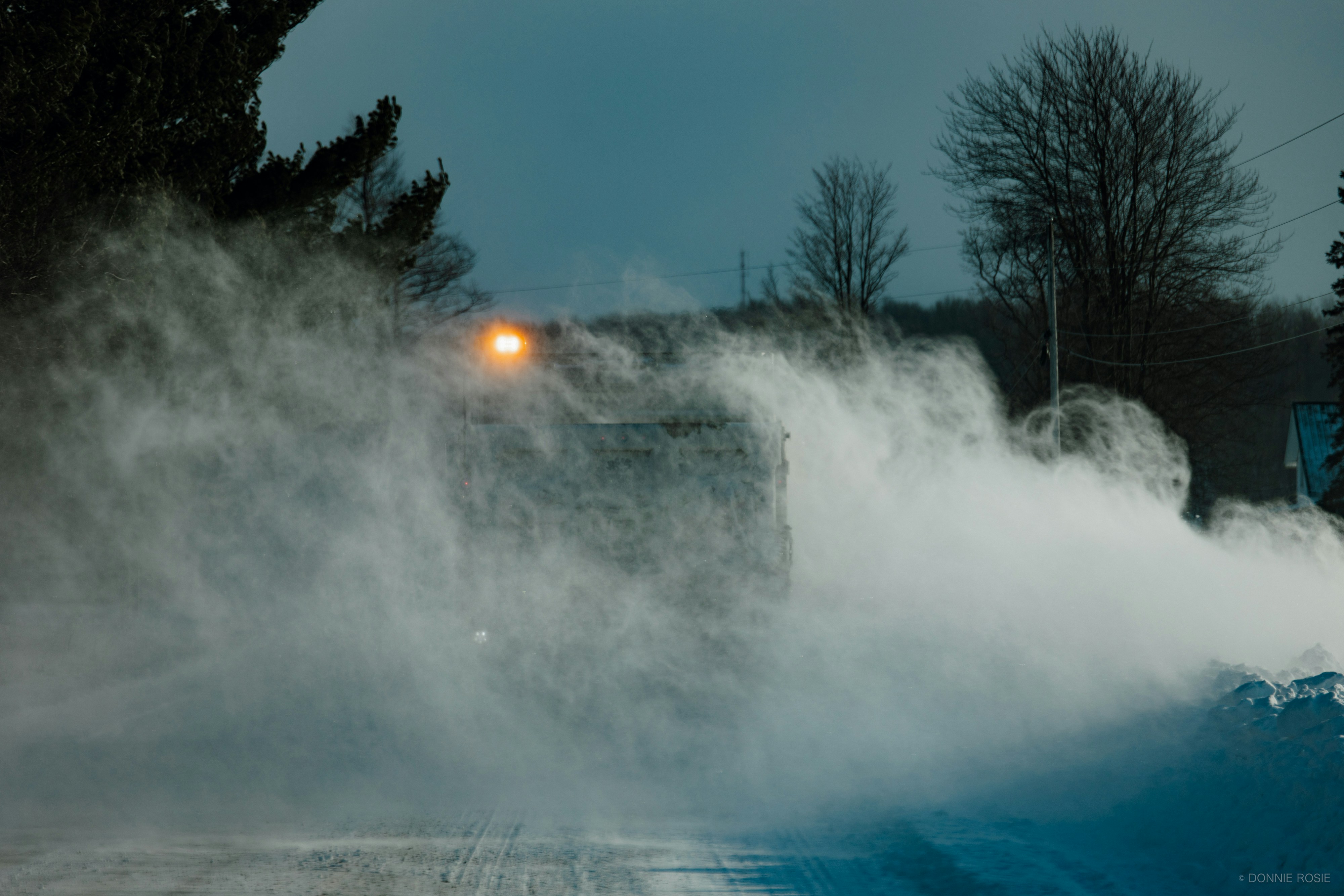 A truck driving through heavy fog at dusk