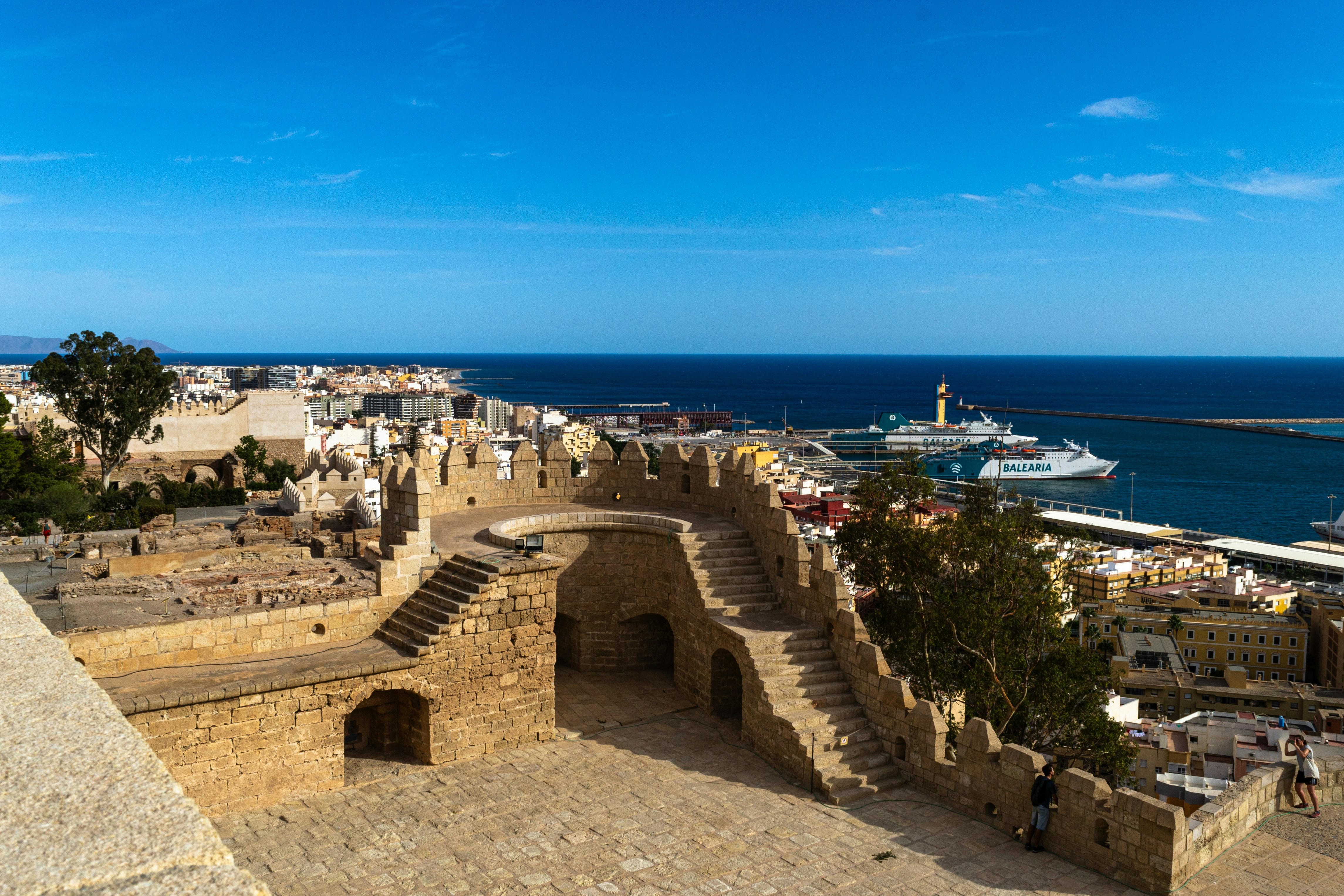 Historic fortress overlooking a bustling harbor with ships.