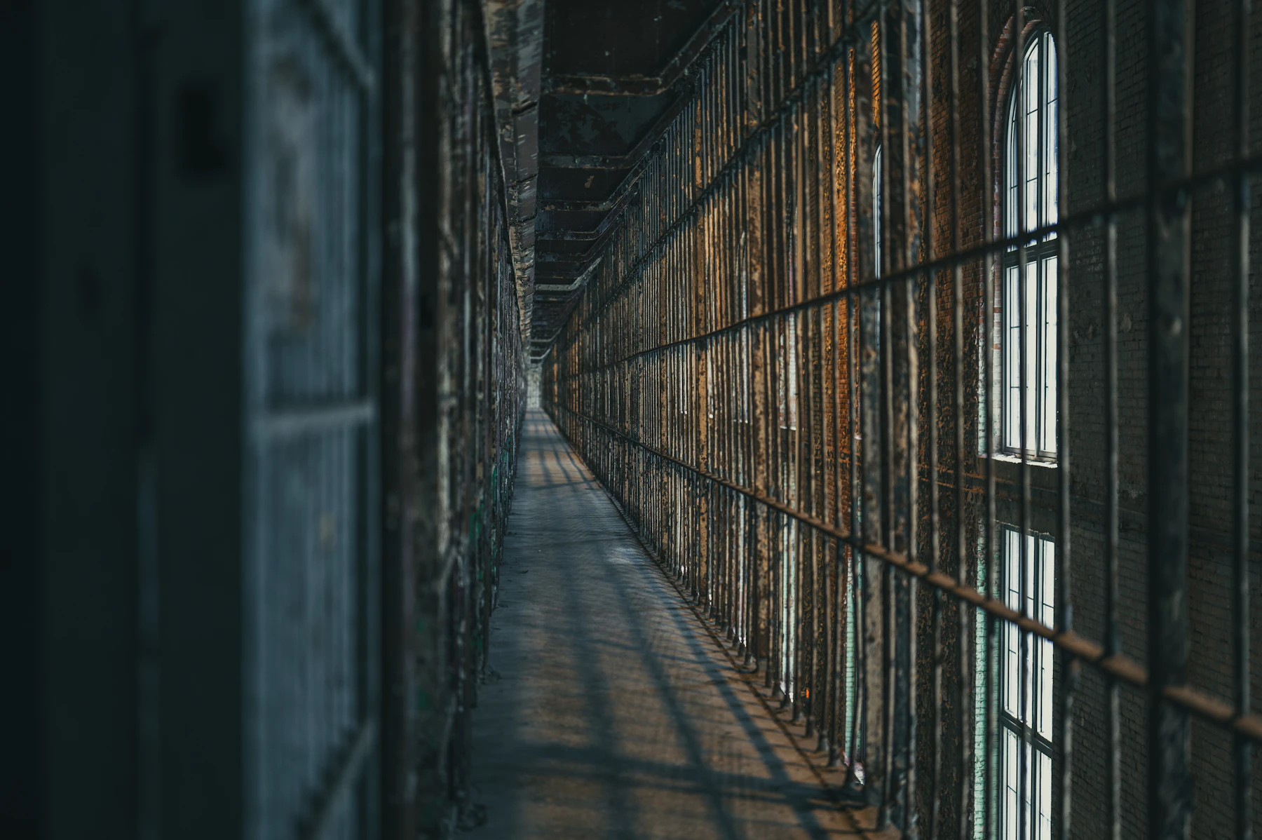 A Dimly Lit Historic Prison Corridor Lined With Barred Cells