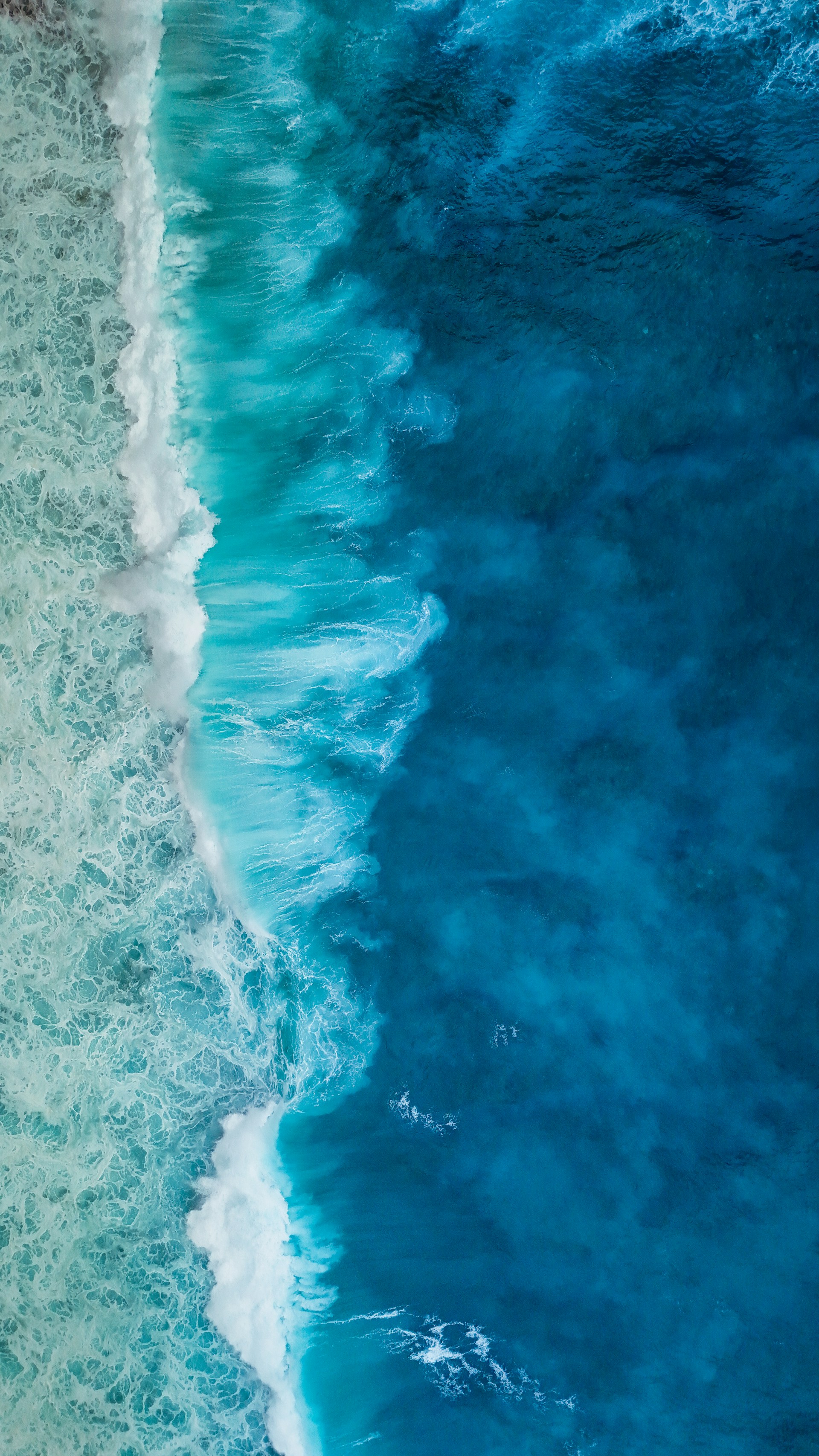 Aerial view of turquoise ocean waves crashing on shore
