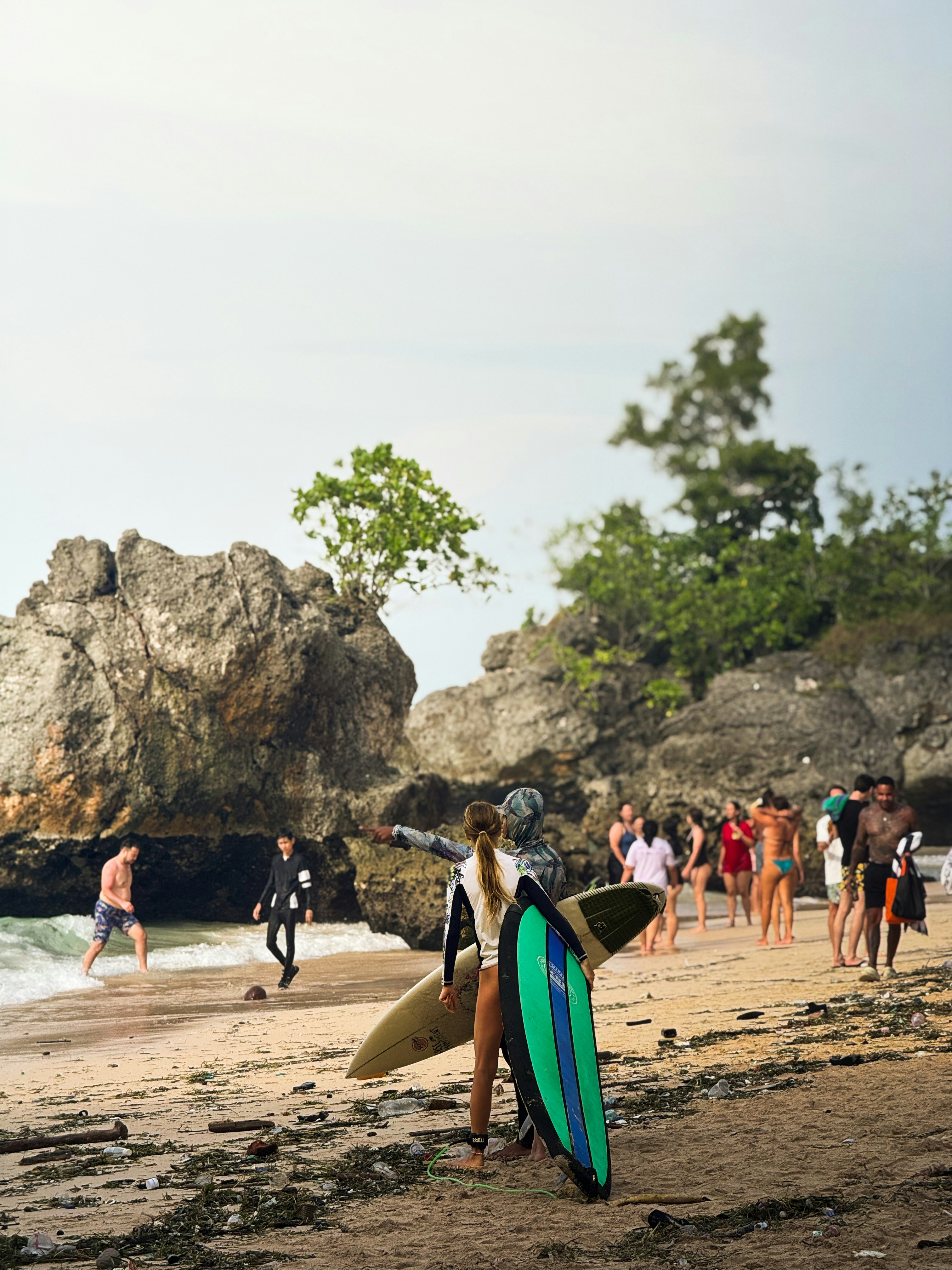 Surfers with surfboards on a sandy beach.