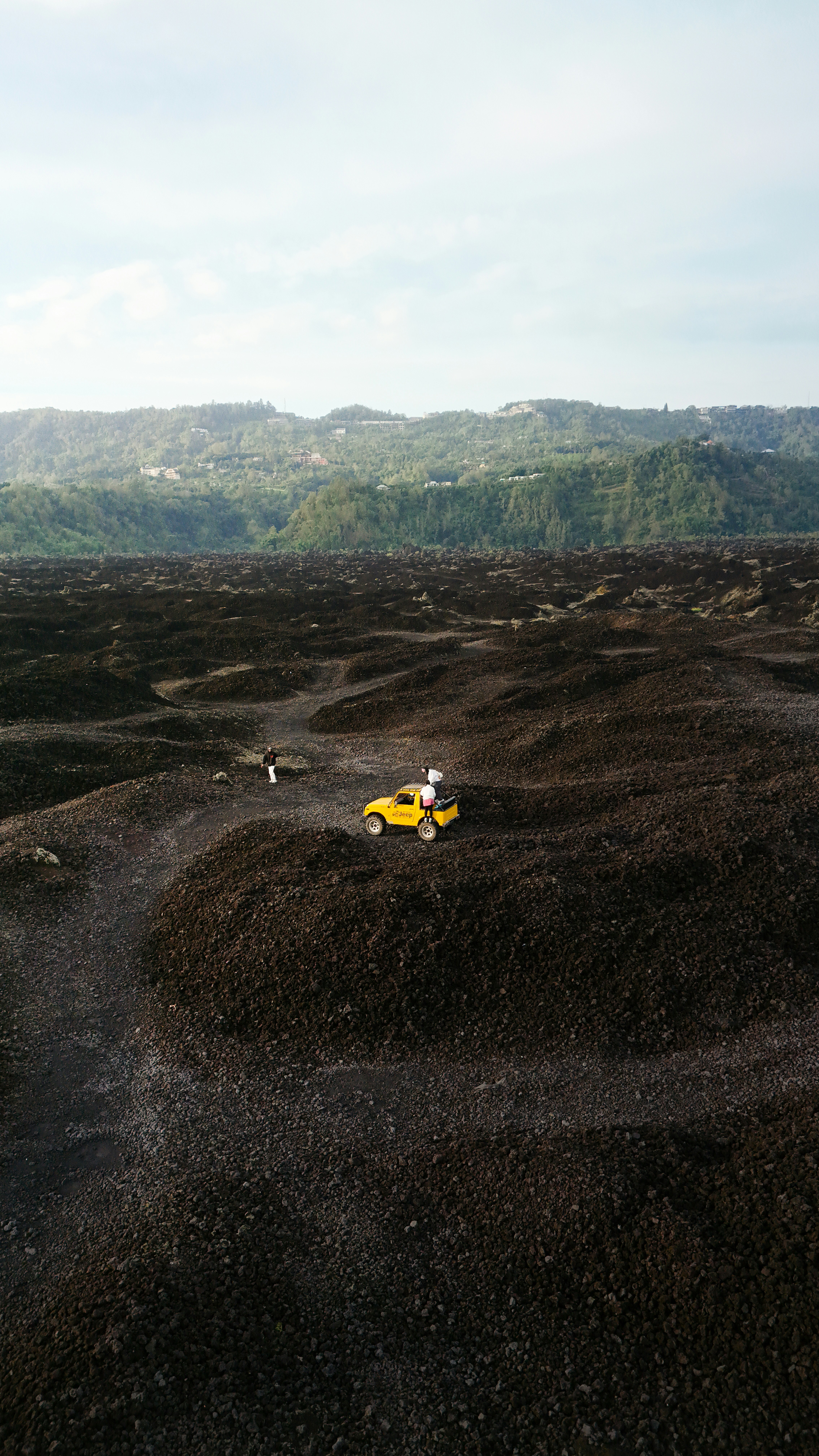 Yellow truck parked on dark, rocky terrain with hills beyond