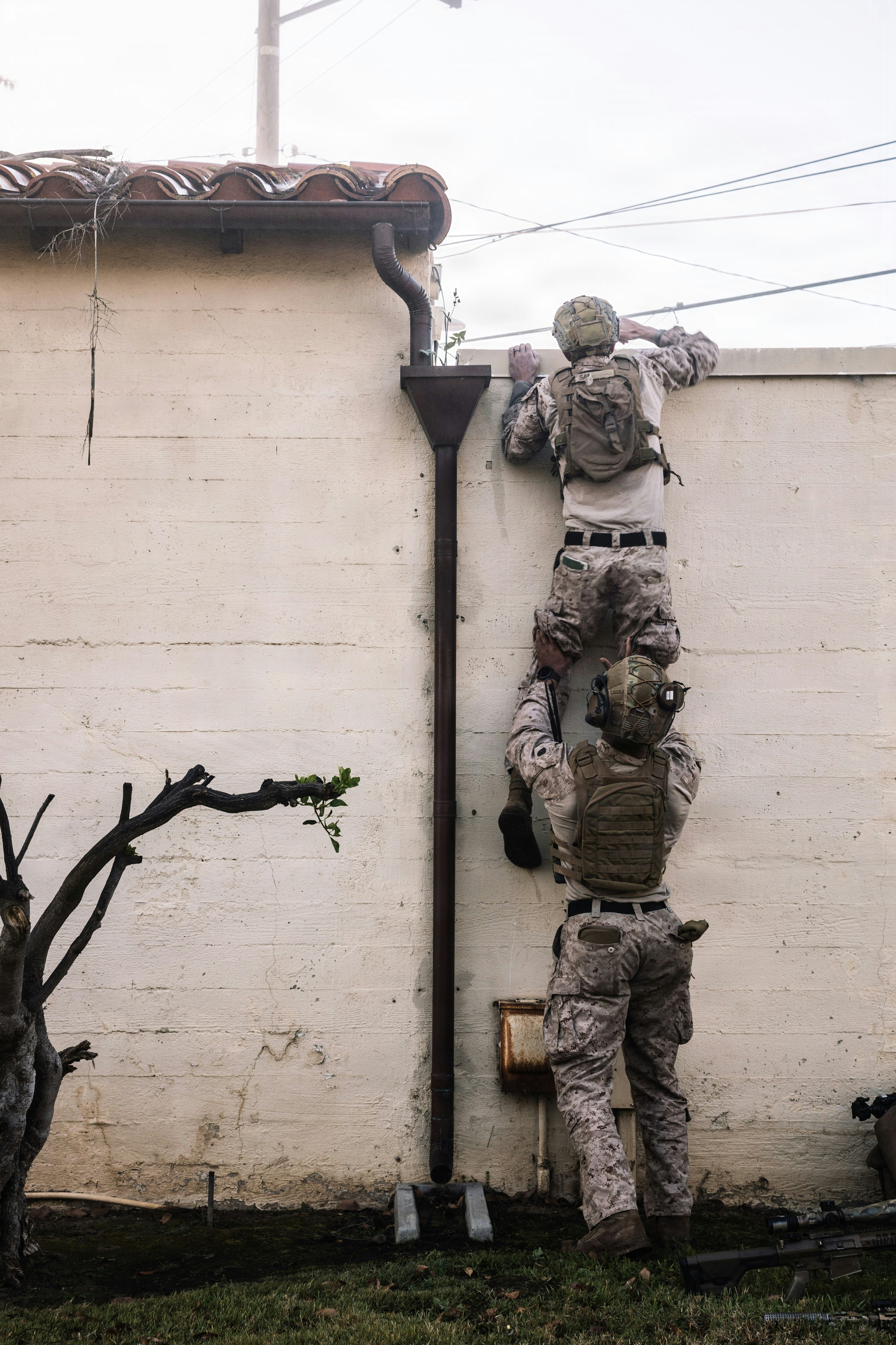 Soldiers climb a wall using a human ladder formation.