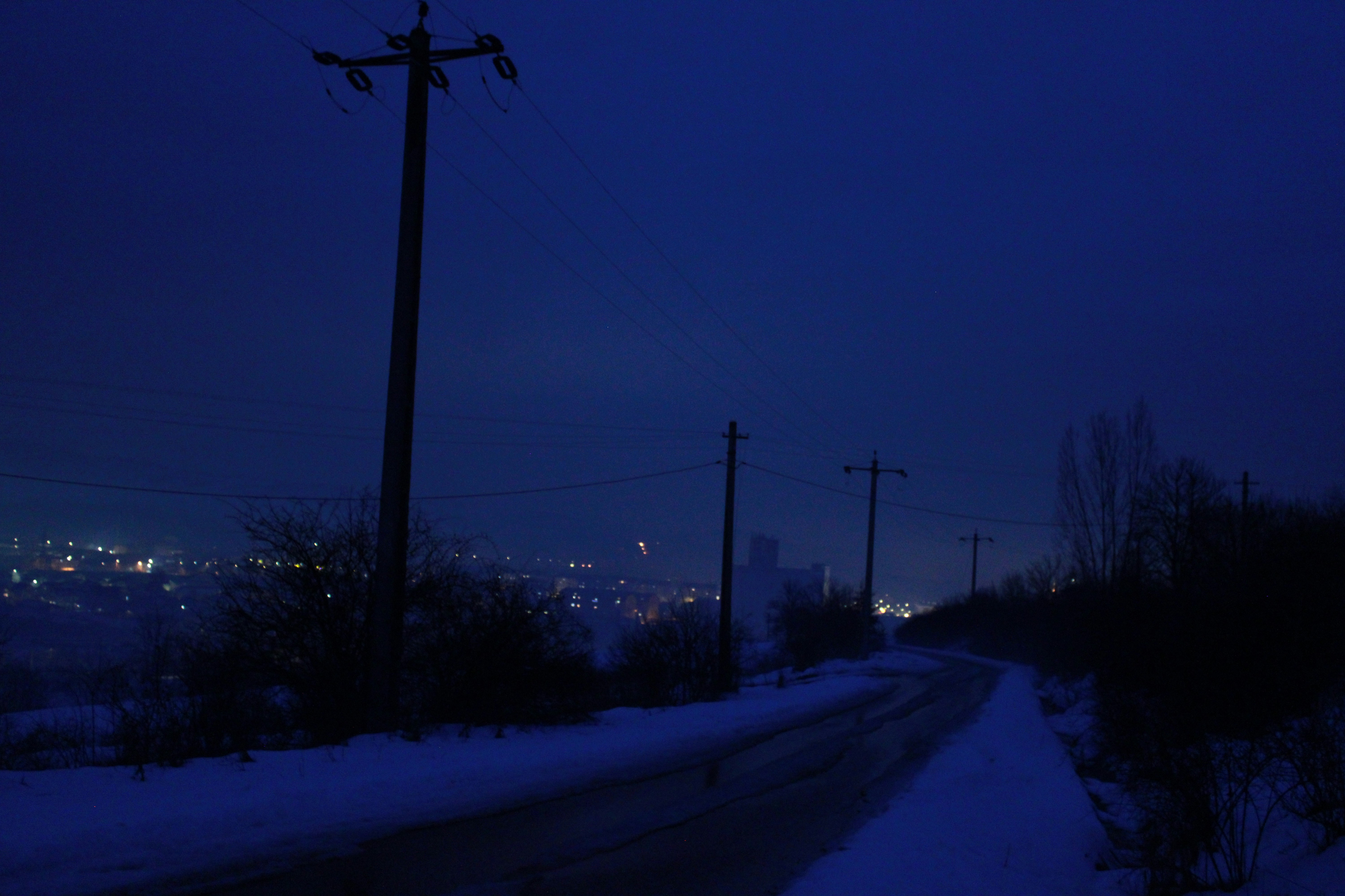 Snowy road with telephone poles at dusk